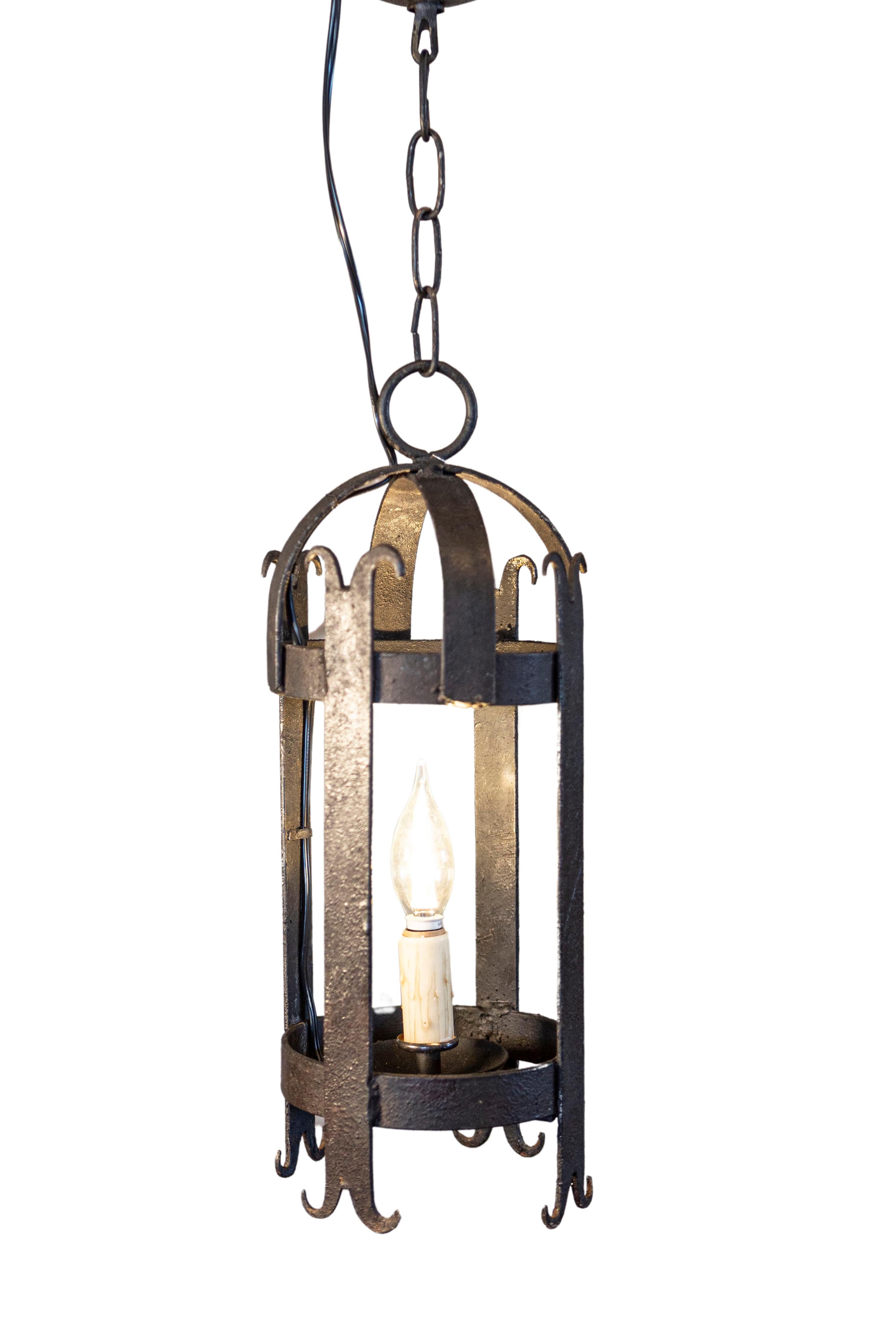 Paire de lanternes cylindriques en fer forgé du 20e siècle, chacune dotée d'une seule lumière. Née en France au cours du XXe siècle, cette exquise paire de lanternes en fer forgé capture l'essence d'une élégance discrète et d'un design intemporel.