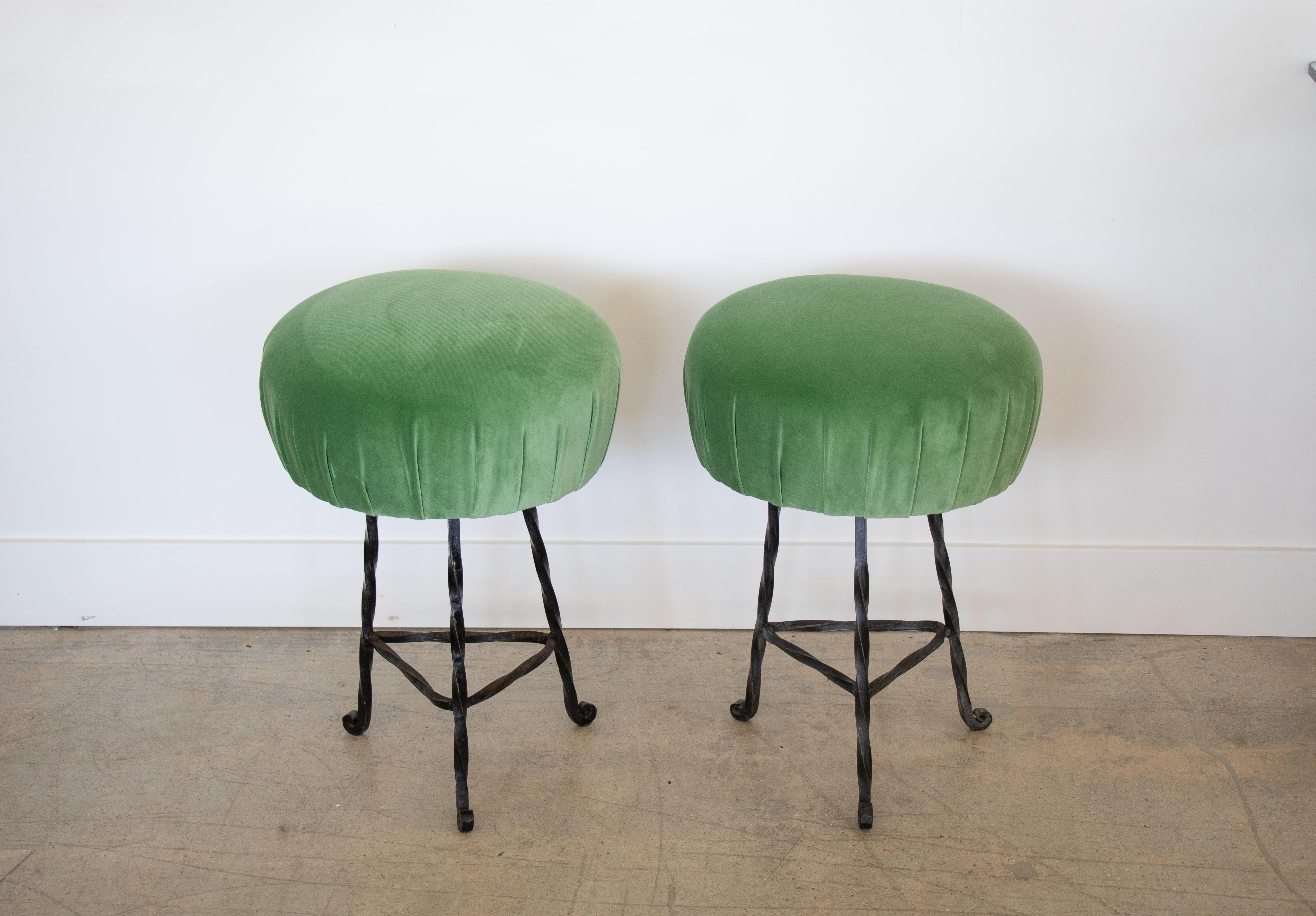 Pair of French twisted iron stools with cushioned. Seats. Black twisted wrought iron base with curled three leg base and newly upholstered round seat in a vibrant green velvet.