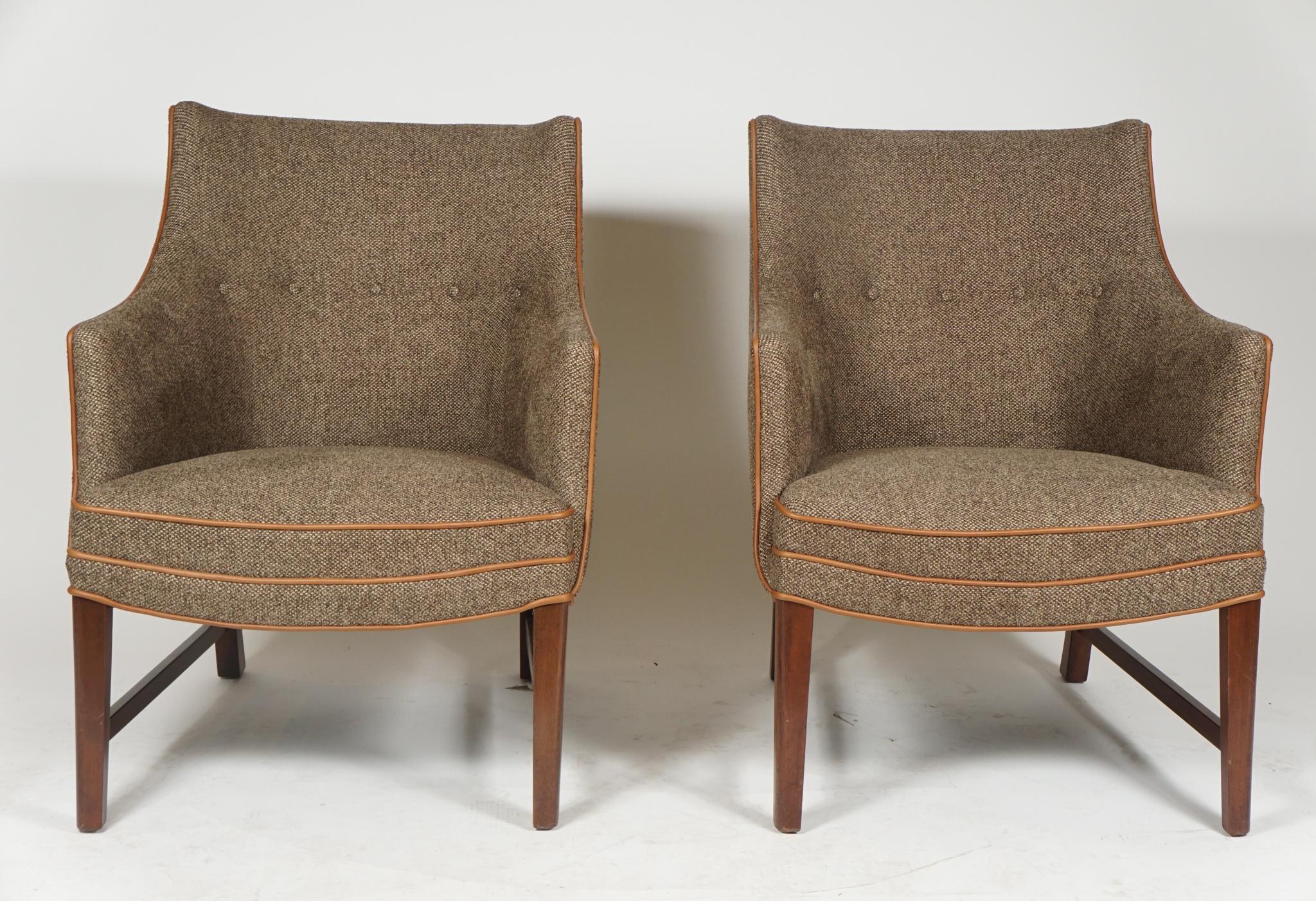 A pair of Danish modern armchairs by noted designer, Frits Henningsen, from the 1940s, newly upholstered in a light beige tweed with beige leather piping and with mahogany frames, the curved arms and relaxed back made for comfortable sitting.