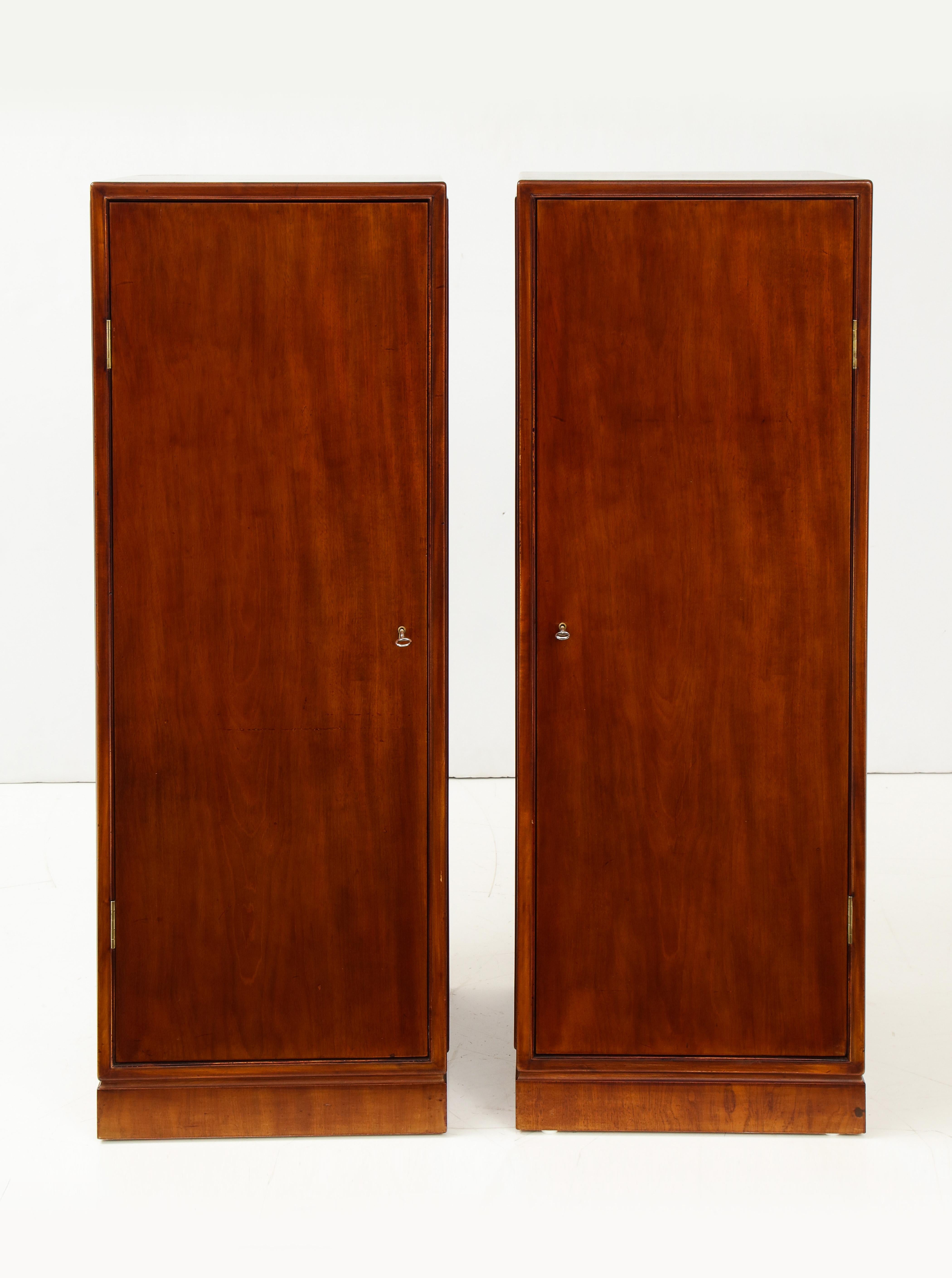 A pair of Danish mahogany freestanding pedestal cabinets by Frits Henningsen, circa 1940s, the square top above paneled sides all around and a single door, raised on a pedestal base. Shelves inside. Two shelves replaced. 
Handsome and restrained