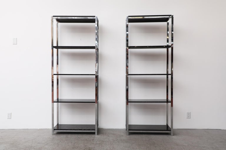 Pair of vintage chrome étagères or bookshelves with faux marble shelves. There is visible scratching to the tops and some of the shelves. All over signs of wear are present, consistent with their age and use.