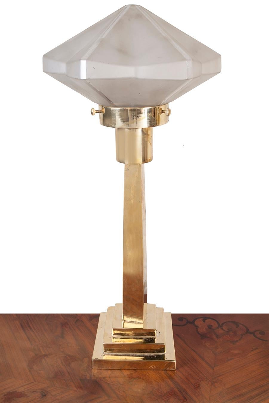 A pair of brass table lamps with frosted glass shades. Shades have an unusual hexagonal shape and dimension with delineations of each quadrant in clear glass. Takes a standard base bulb and have been rewired for American use. Originally European.