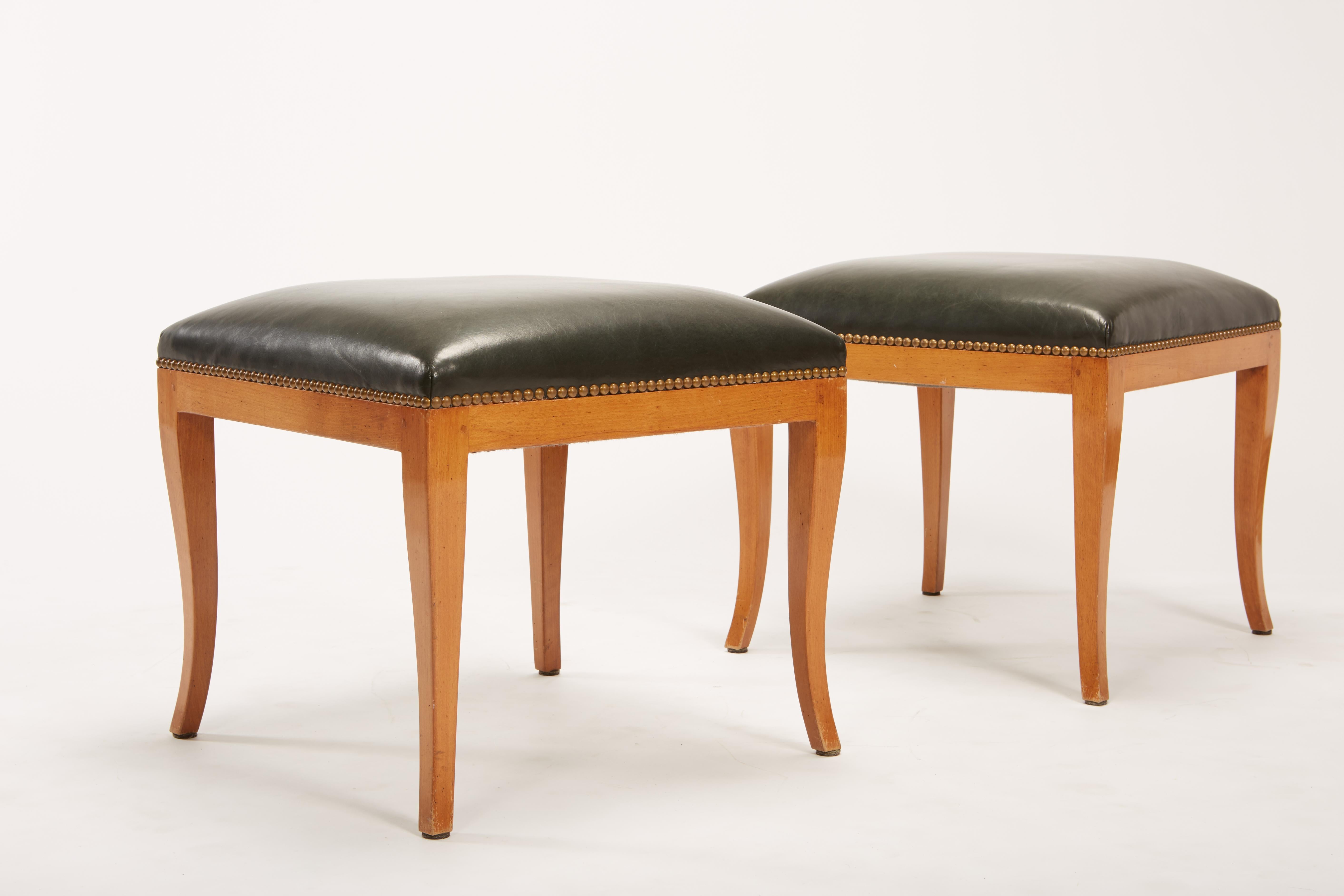 Pair of fruitwood Biedermeier style ottomans or stools with blackish green leather and bronze tone brass tacks. Construction of legs includes square pegs for mortise and tenon joints. Restored in 2004, with new leather, brass tack and refinishing.