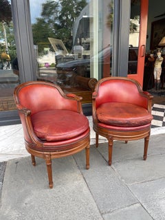 Pair of fruitwood swivel chairs in ox blood leather with Gouffe label