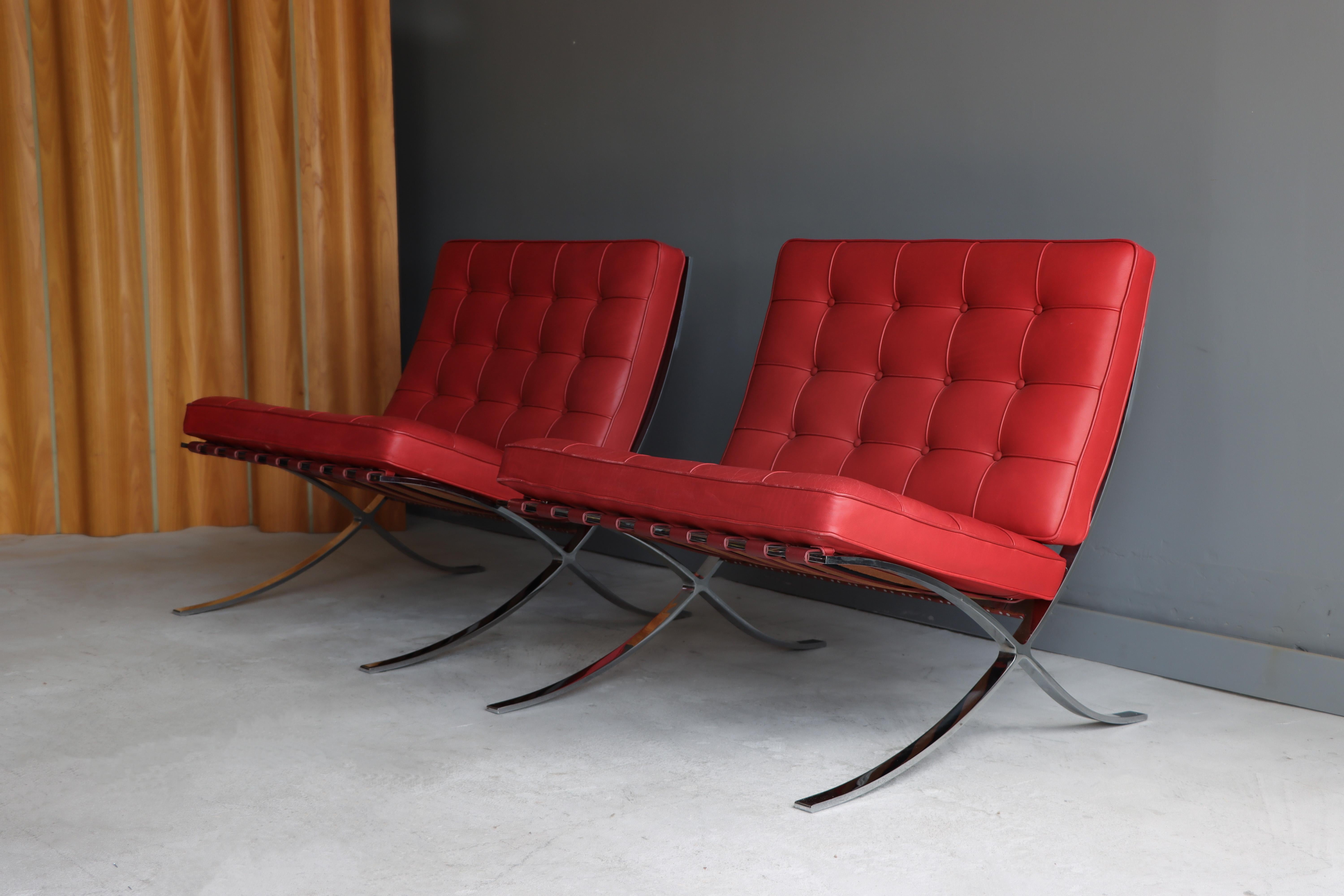Pair of original and uncommon leather color Barcelona chairs designed by L. Mies van der Rohe for Knoll. 

 Red leather with attractive wear (please see photos). Chromed steel frames. Unique and rare opportunity. Fully labeled on undersides of