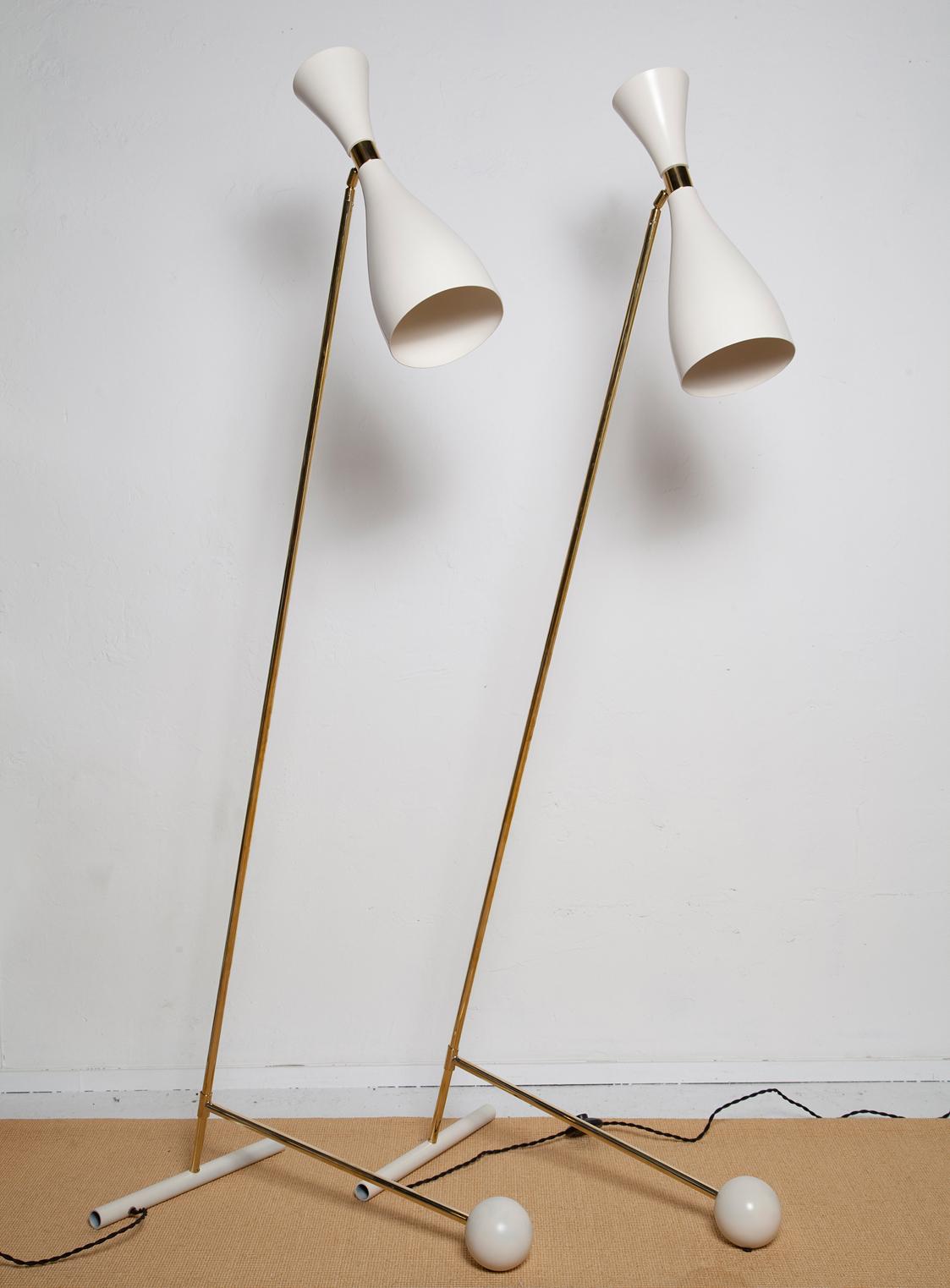 Fully restored brass and cream enameled, 1950s Italian floor lamps in the manner of Stilnovo. Counterweight design allows for height adjustability while shades swivel 180 degrees for multi-Directional lighting. New U.S. wiring, with both upper and
