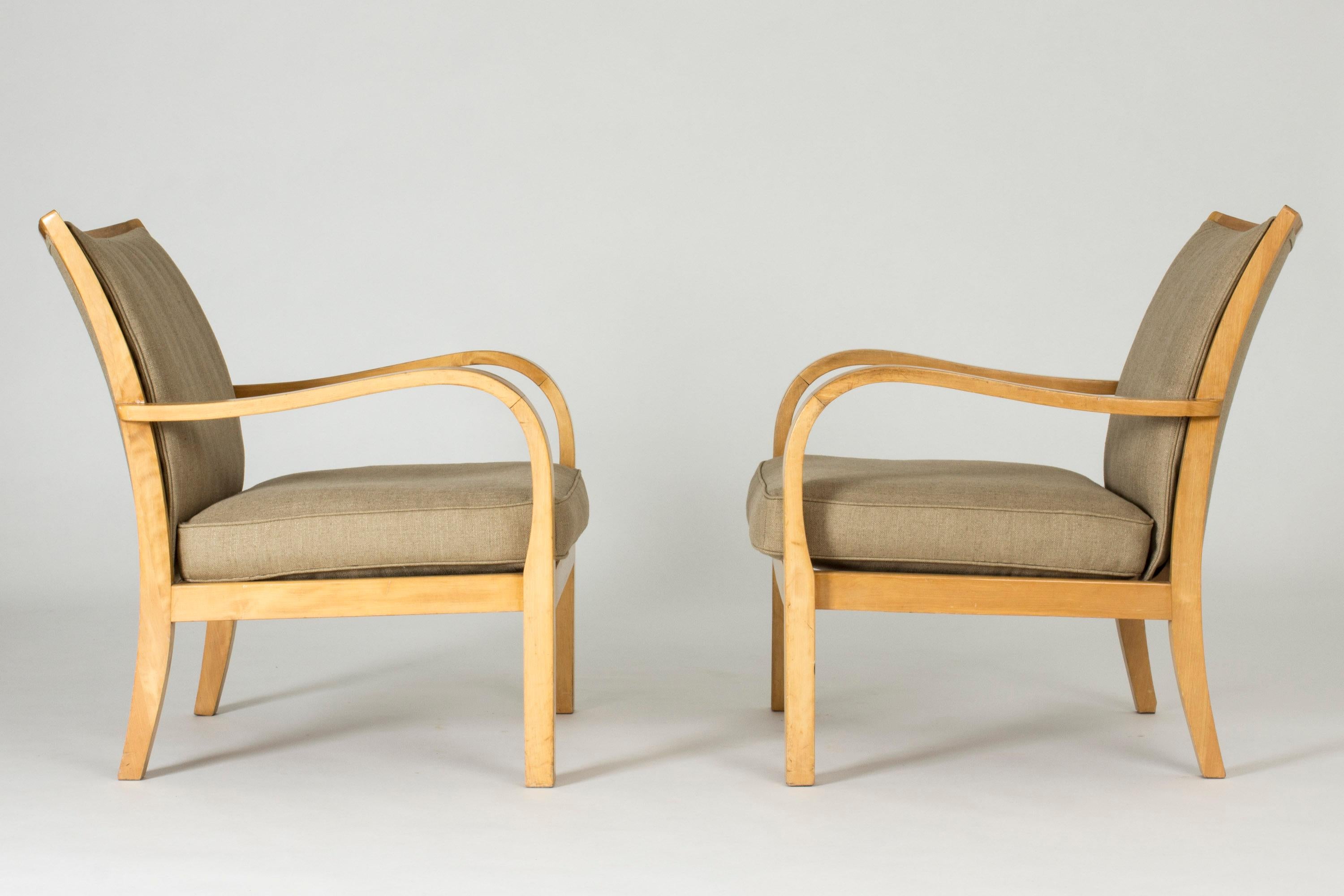 Pair of beautiful lounge chairs by Axel Larsson, with curved armrests creating striking, open and elongated silhouettes. Made from birch, upholstered with linen fabric.
 