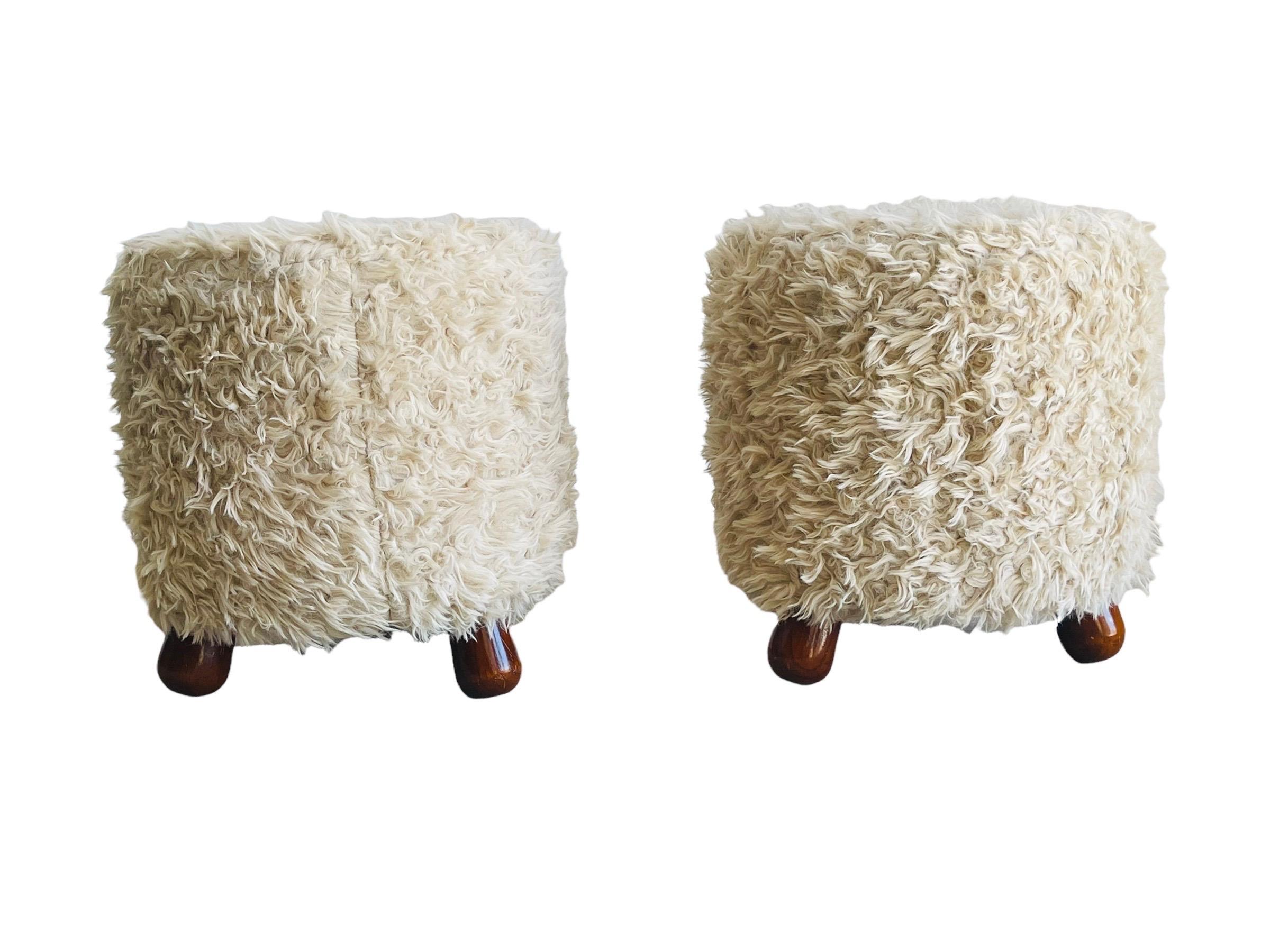 Pair of Fuzzy stools. The stools sit in a tripod turned legs and upholstery in creamy fuzzy upholstery. The stools are in good vintage condition with normal wear consistent with age and use. 

Measures: 15” tall x 13” round.