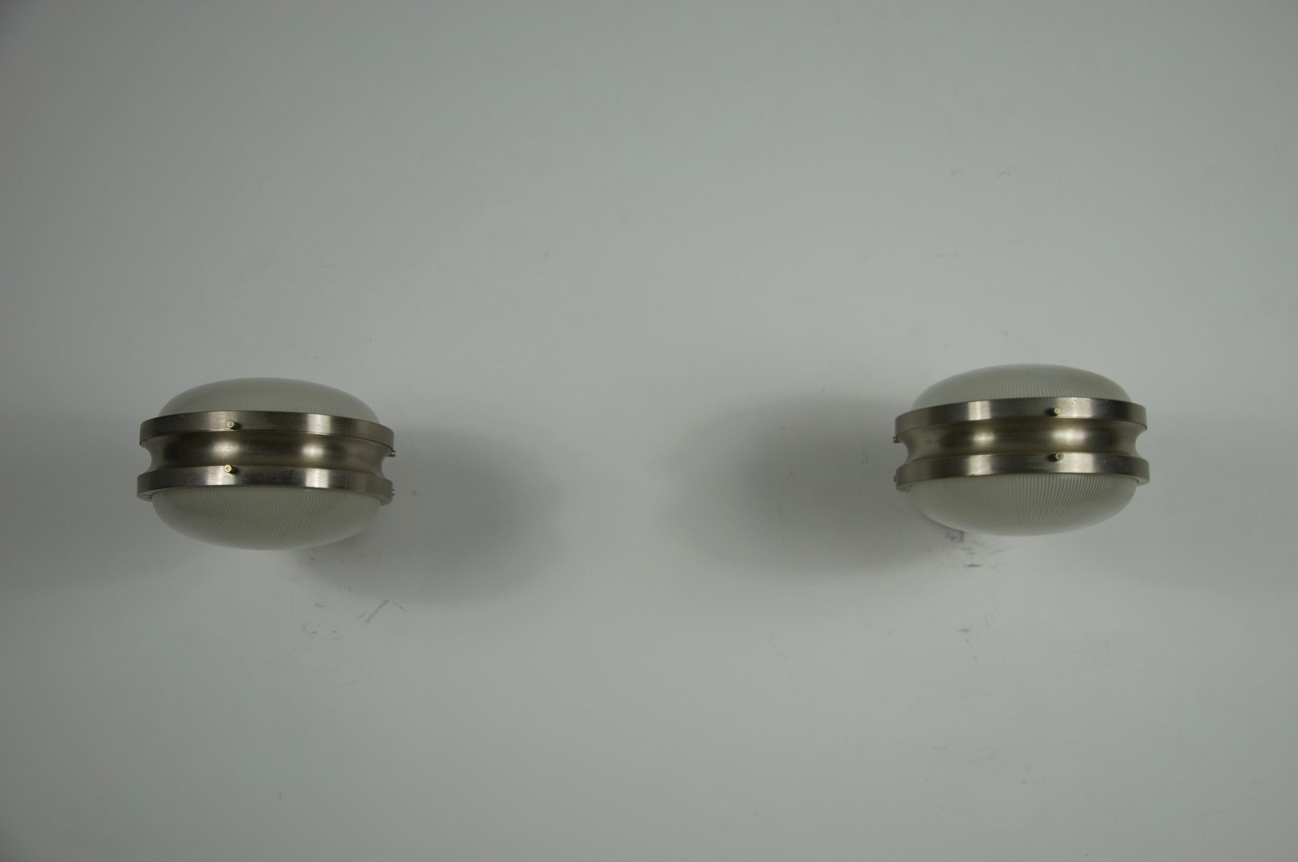 This striking pair of Gamma wall lights was designed by Sergio Mazza for Artemide in the 1960s and showcases the refined modernism of mid-century Italian design. Each fixture features a beautifully textured pressed-glass diffuser encased in a solid