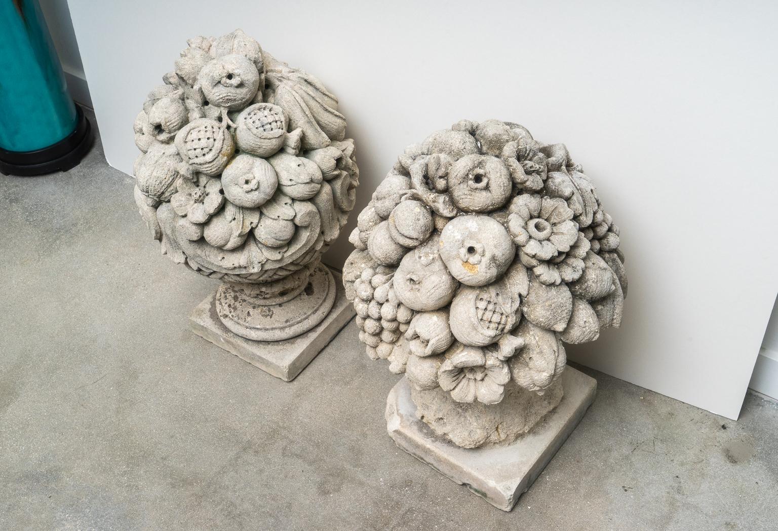 This stylish set of garden sculptures were acquired from a Palm Beach estate and they date to the early part of the 20th century. The pieces are a cast stone with various fruits and flowers.