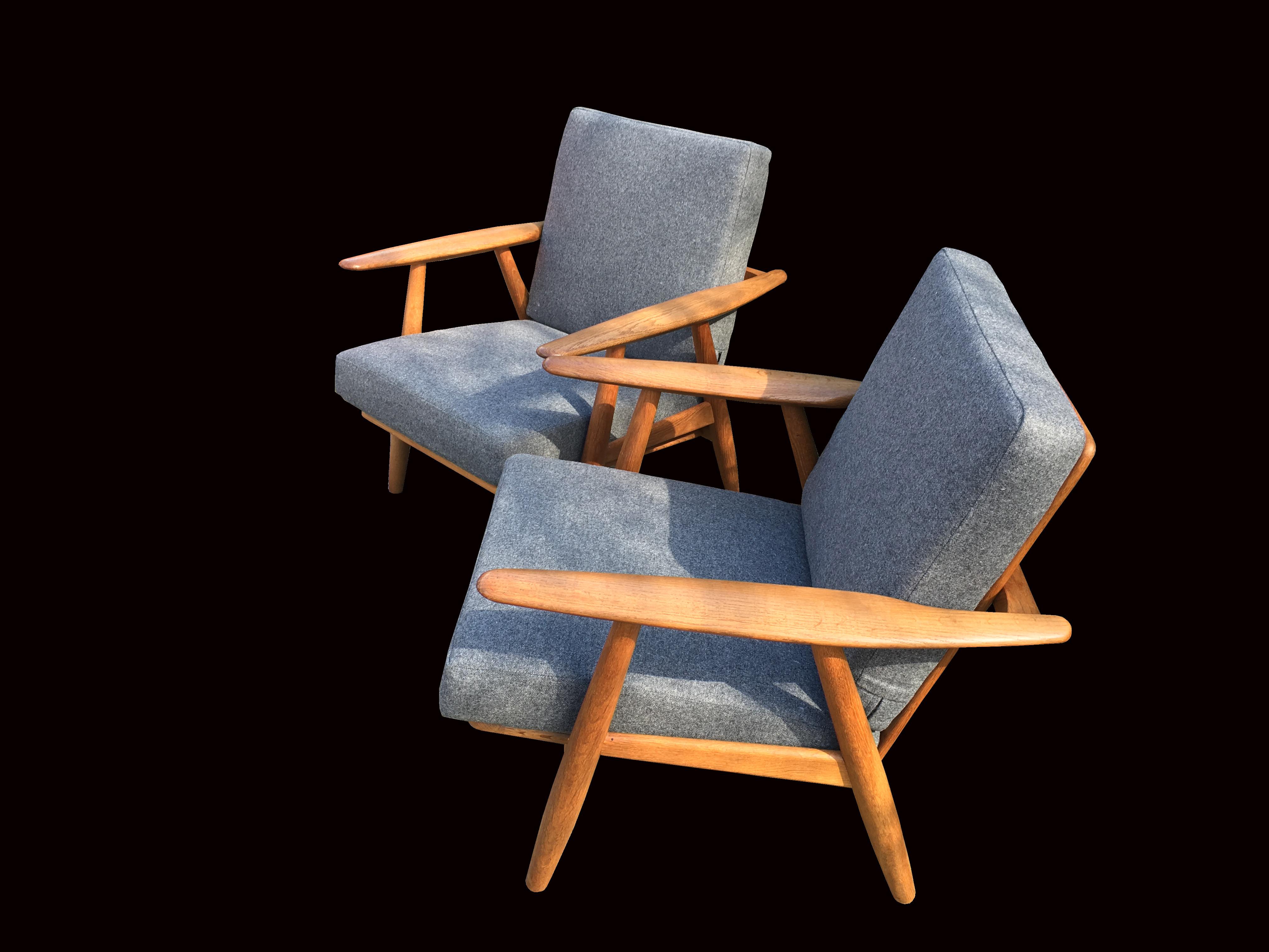 A very nice original pair of one of Hans J Wegners most sought after designs manufactured by GETAMA. This pair have beautiful golden brown patina oak, and the original comfortable sprung cushions have been recovered in New grey Wool.