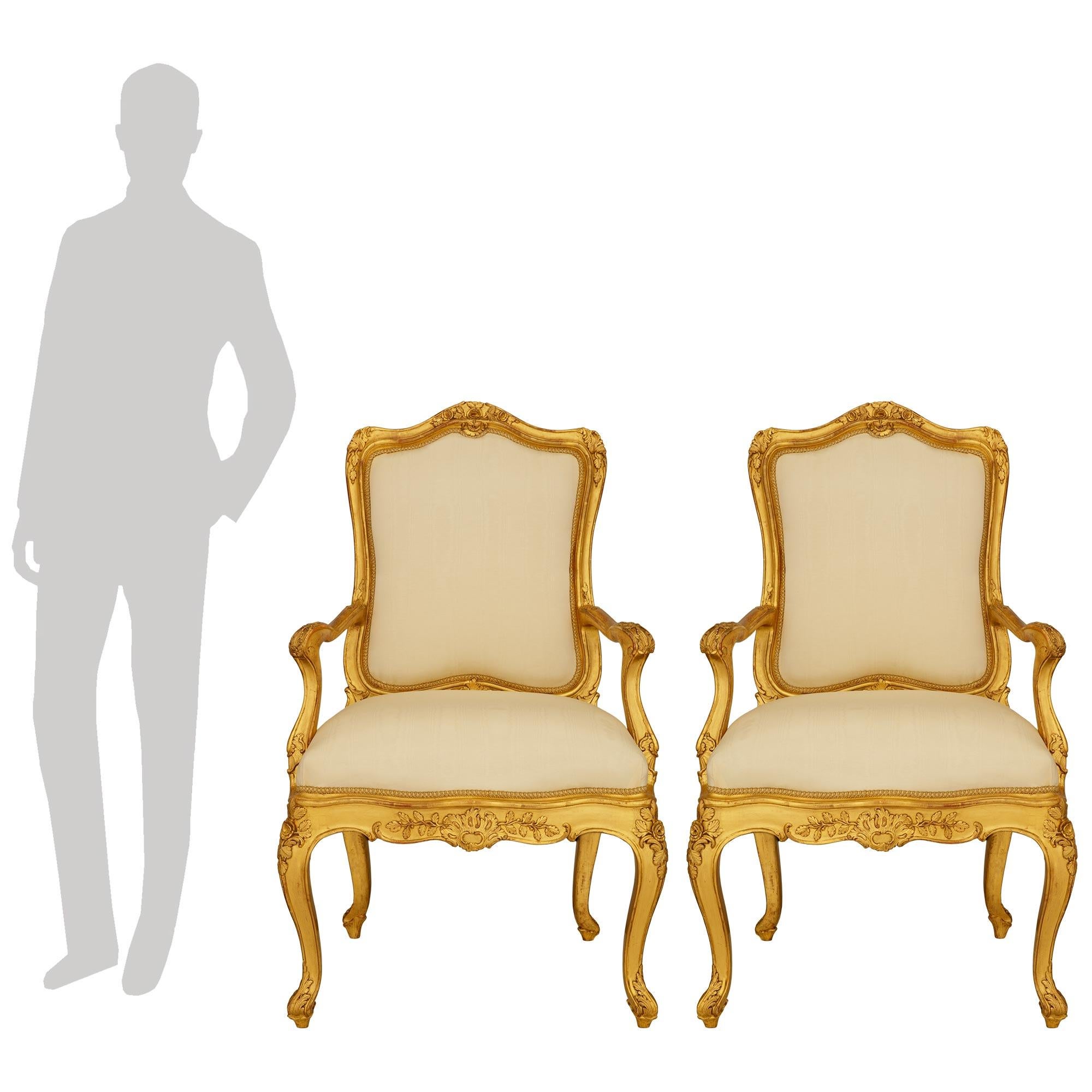 Elegante pareja de sillones genoveses de madera dorada de estilo Luis XV del siglo XIX. Este impresionante par de sillones de respaldo alto, procedentes de Génova, se elevan sobre cuatro patas con roleos, con la parte inferior envuelta en hojas de