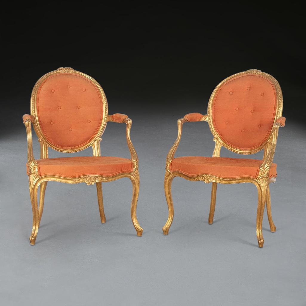 A smart pair of C18th giltwood open armchairs, well carved throughout, the curved oval backs with gadrooned mouldings and foliate paterai to the tops, leading to shapely arms with acanthus carving and moulded supports, above carved shells to the