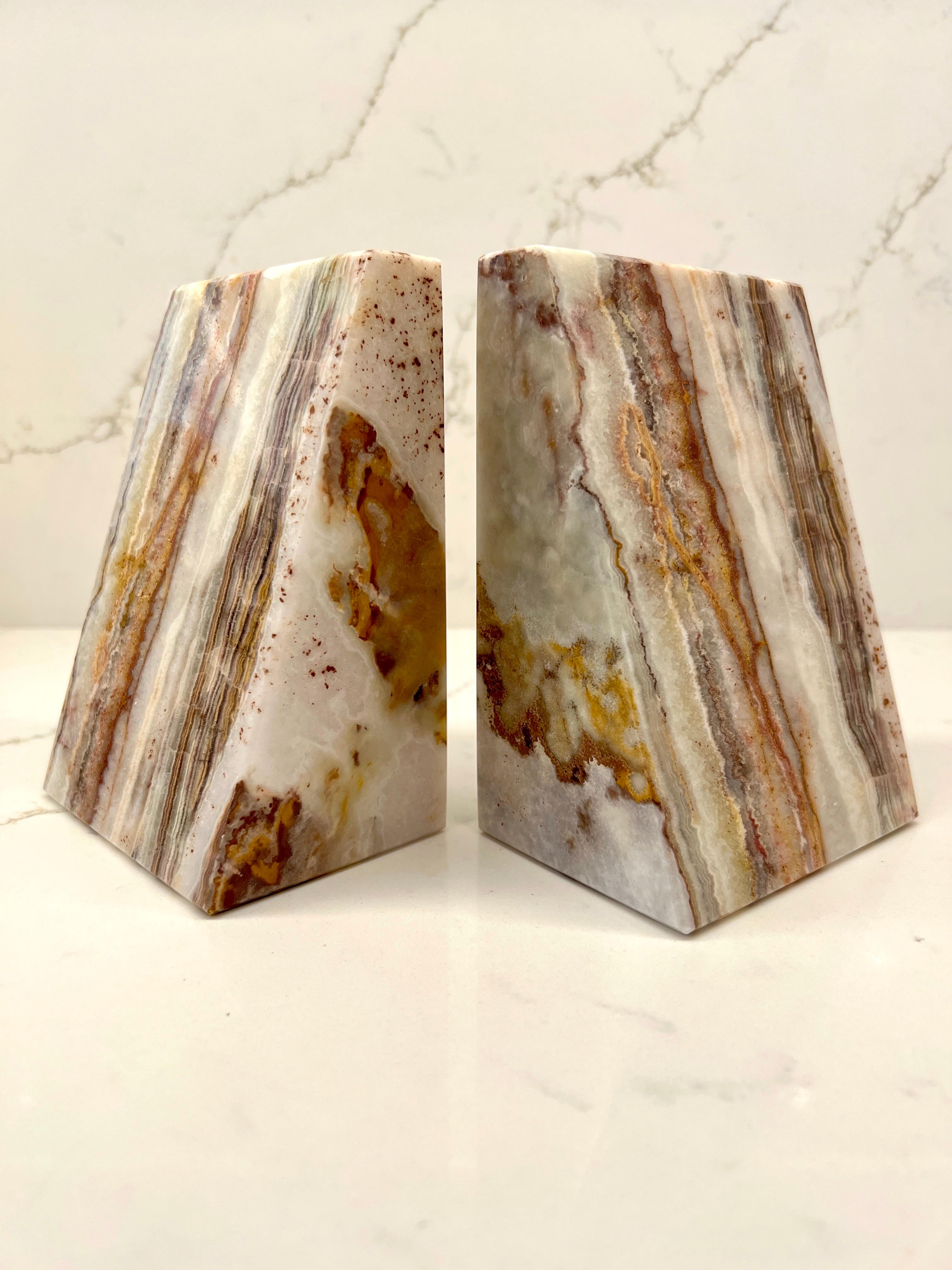Handcrafted genuine onyx bookends with geometric design. Carved and polished natural striped onyx. Each piece is unique and features variegated colors in white, beige, tan, brown, and taupe. Makes a chic desk or bookcase accessory.