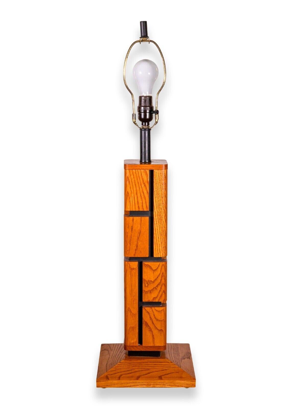 A pair of geometric wood puzzle table lamps. A lovely pair of table lamps featuring a unique geometric design with a natural wood grain on the outside, and a black finish on the inside. These lamps have a square wood base with small rubber feet on