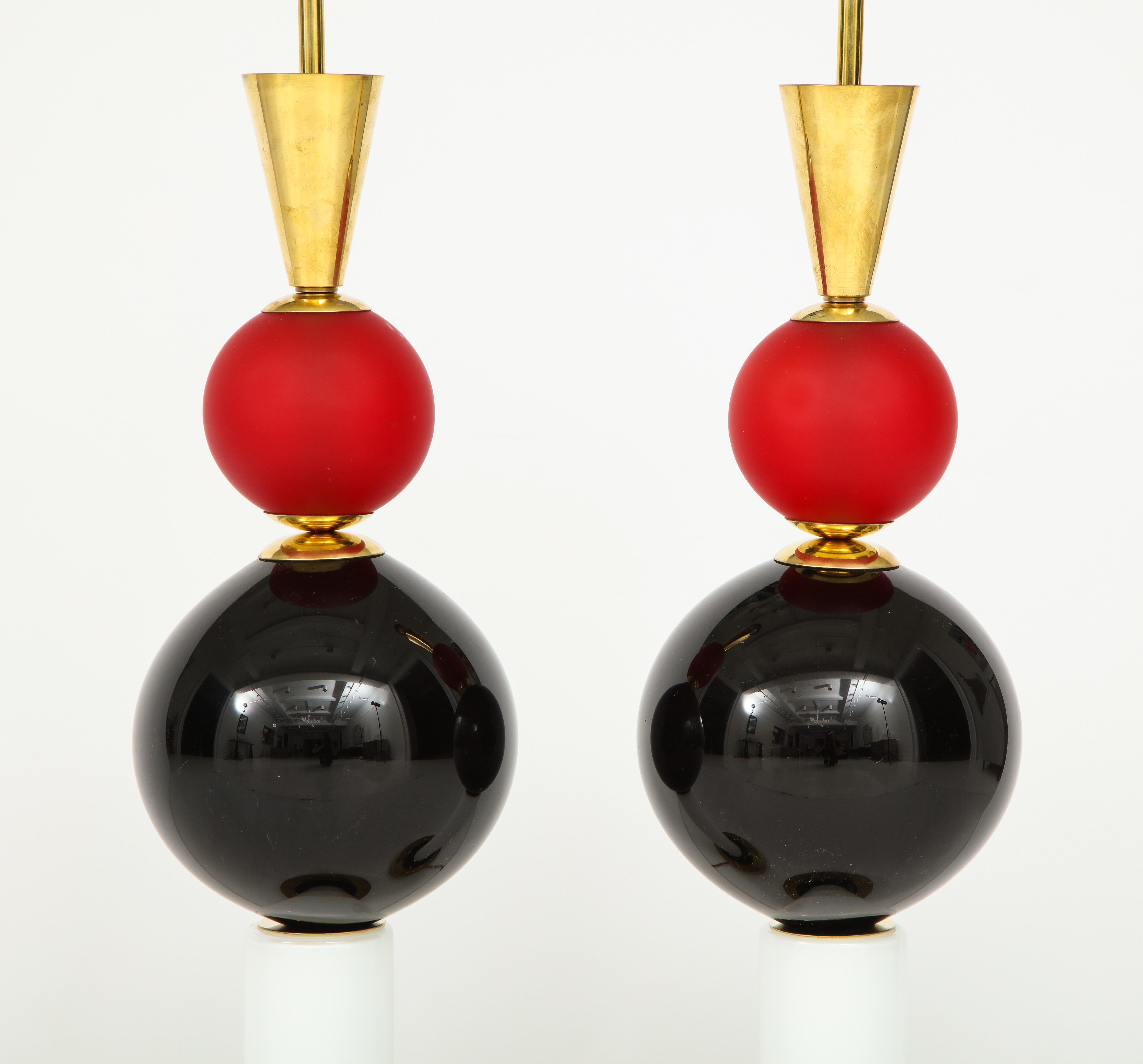 Questa audace coppia di lampade in vetro soffiato a mano di Murano è composta da elementi in vetro rosso smerigliato, nero lucido e bianco smerigliato con una struttura in ottone naturale non laccato. Queste lampade uniche nel loro genere sono state