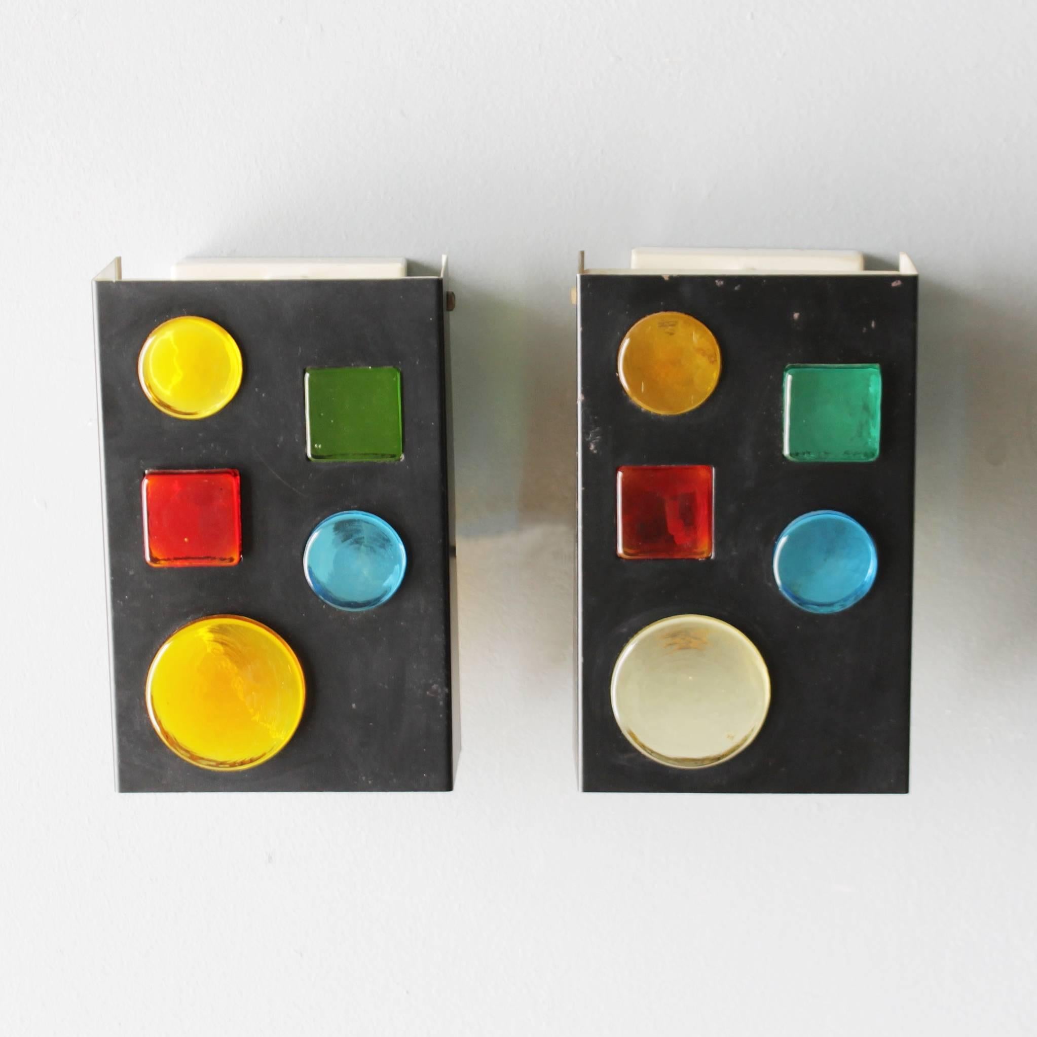 Pair of very rare geometric sconces by RAAK Amsterdam, the Netherlands. Colored glass geometric shapes in a black lacquered rectangular metal lamp. 
One bulb, 40 watt, E14 14-17 mm Small Edison Screw (SES).
Dimensions: Height 7.9 in. (20 cm),