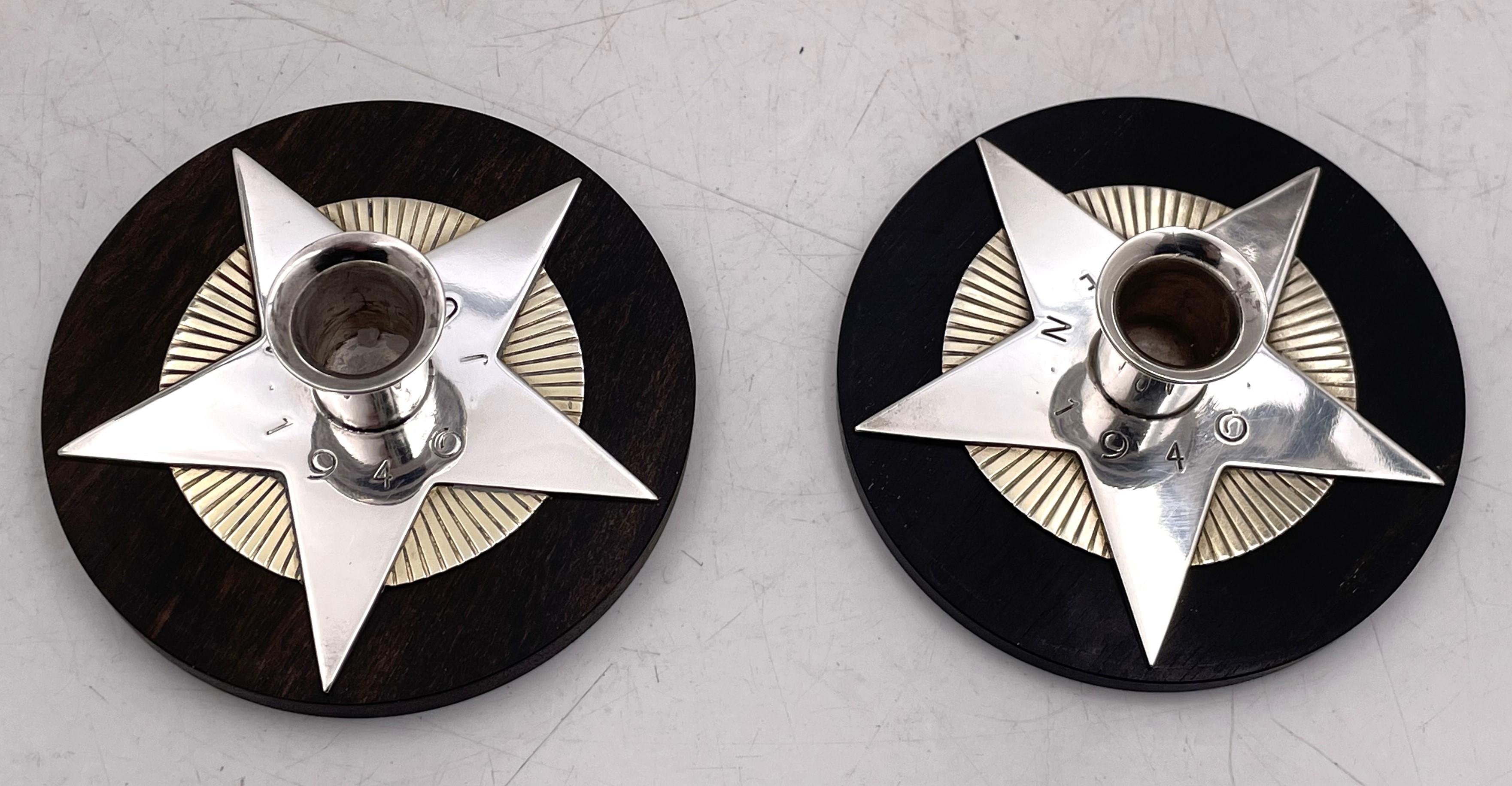 Rare paire de bougeoirs en forme d'étoile en argent sterling de Georg Jensen sur des bases en bois, conçus par Arno Malinowski, datant de 1940. Ils mesurent 3'' de diamètre par 1 1/8'' de hauteur et portent les poinçons indiqués. 

L'orfèvre danois