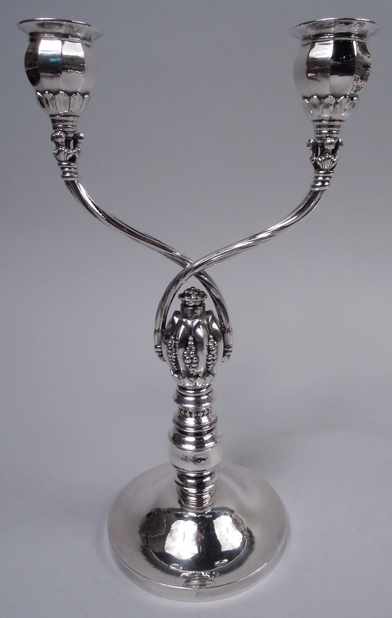 Pair of Art Deco sterling silver 2-light candelabra. Made by Georg Jensen in Copenhagen, ca 1950. Each: Two crisscrossing arms with twisted fluting each terminating in single faceted socket with wide flat rim; socket set in leaf ring. Arms mounted