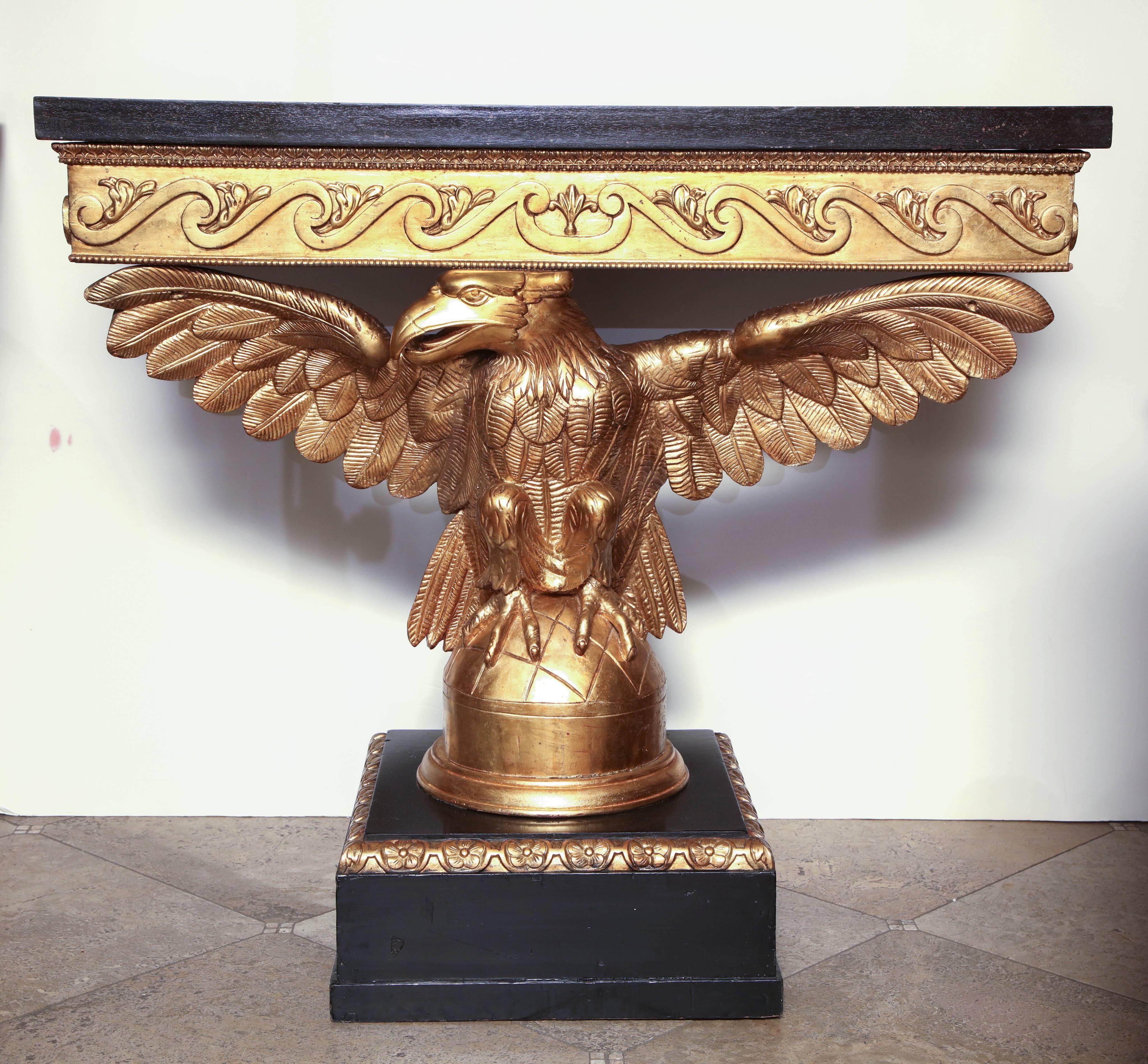 Pair of George I style carved and gilded eagle consoles with painted faux marble top, carved Vitruvian scrolls on a square plinth base.
 