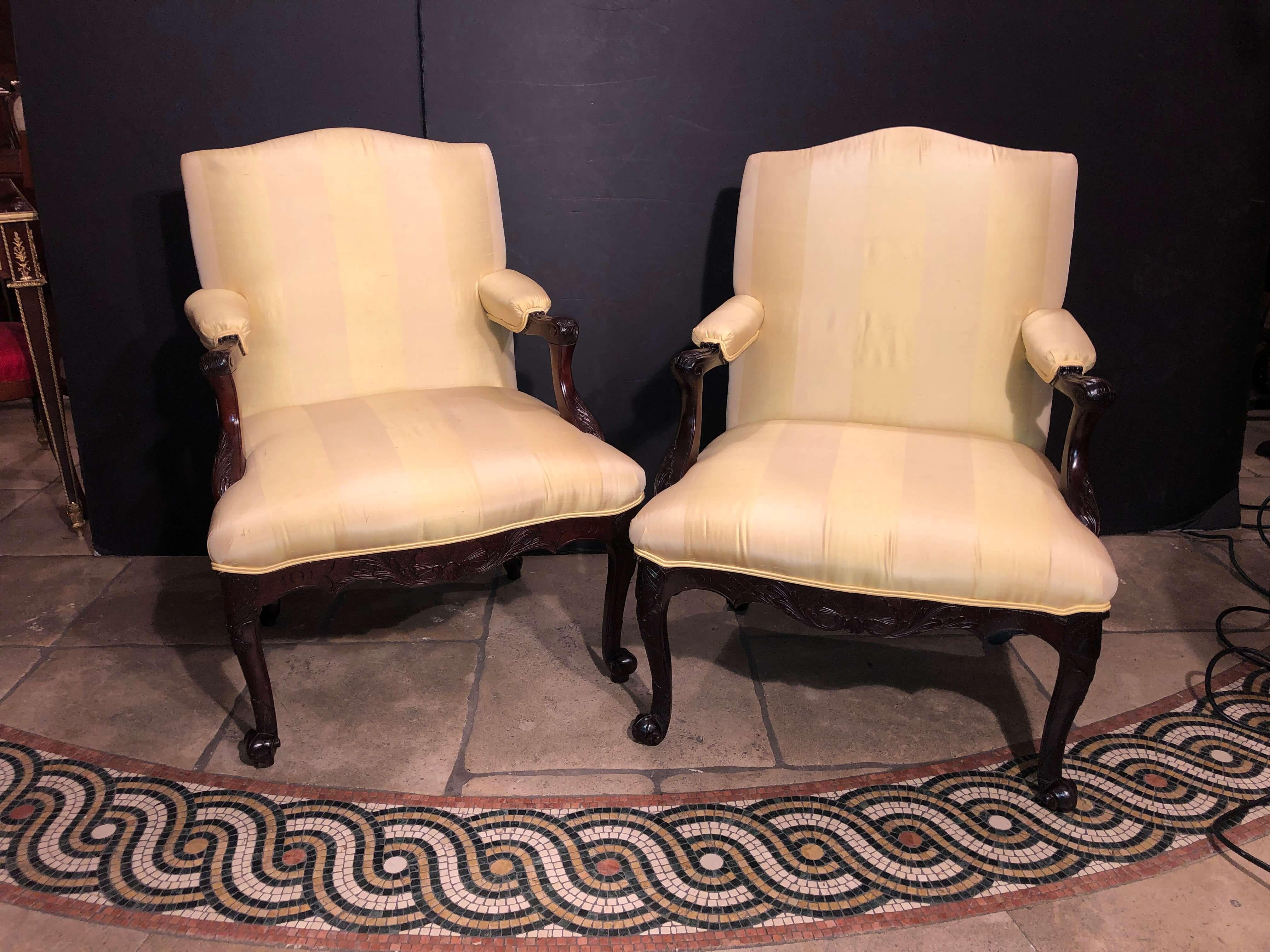 Pair of Irish George II carved mahogany scroll foot armchairs, with upholstered back, seat and armrests, with shell carved sides and knees and acanthus wrapped arms with boldly carved scroll feet.
One 18th century, one later.