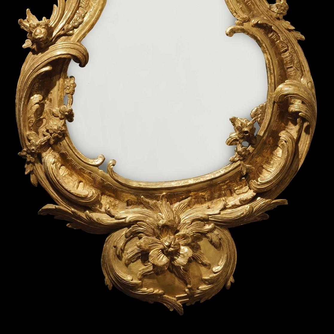 A pair of George II style mirrors

Constructed in carved giltwood, the waisted teardrop shaped mercury plates housed within asymmetrical conforming frames in the George II manner richly carved with scrolling foliates and flowering branchwork;
