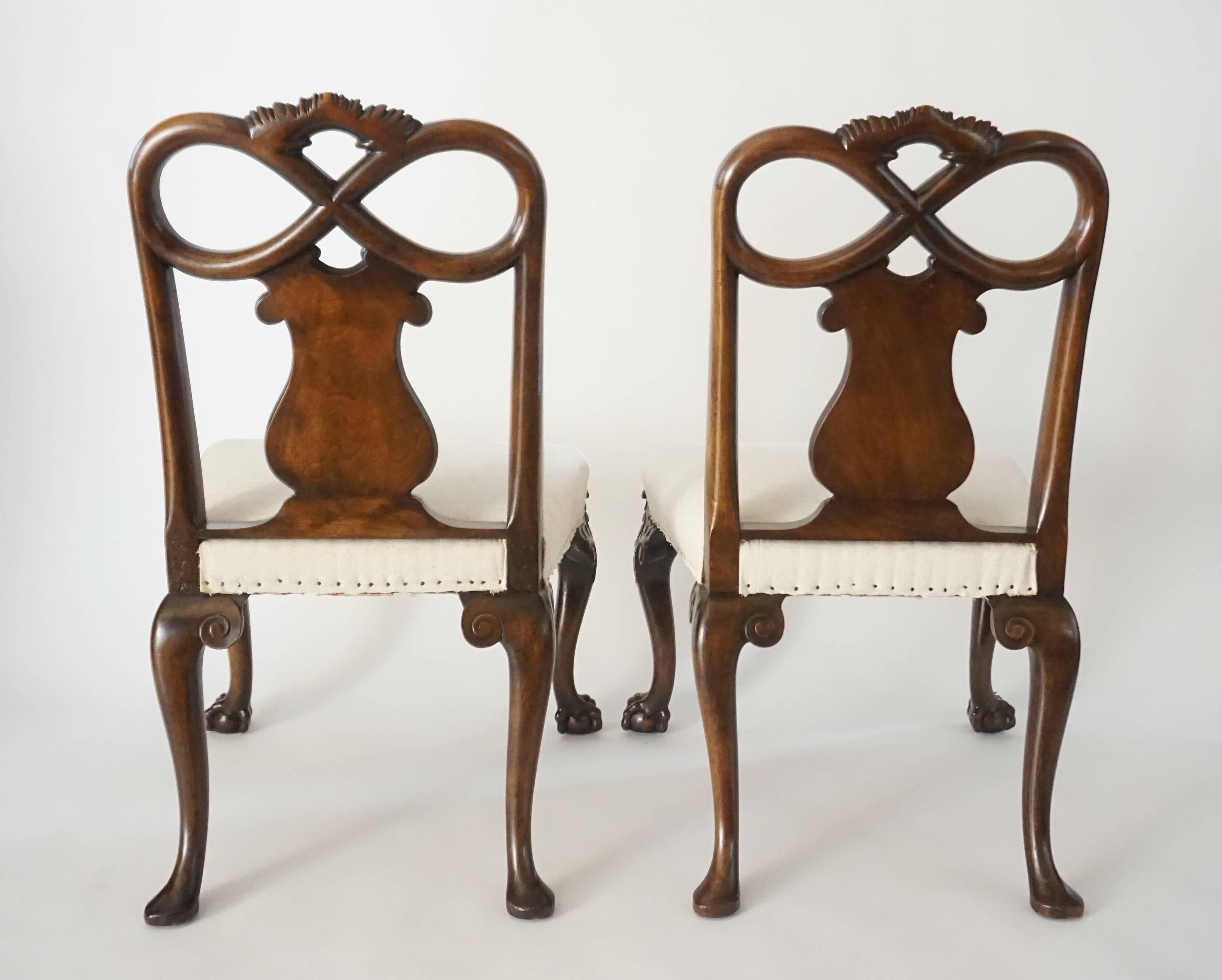 An exceptional pair of English George II, circa 1740, Rococo style bench-made side chairs having exquisitely carved walnut frames with Rococo 