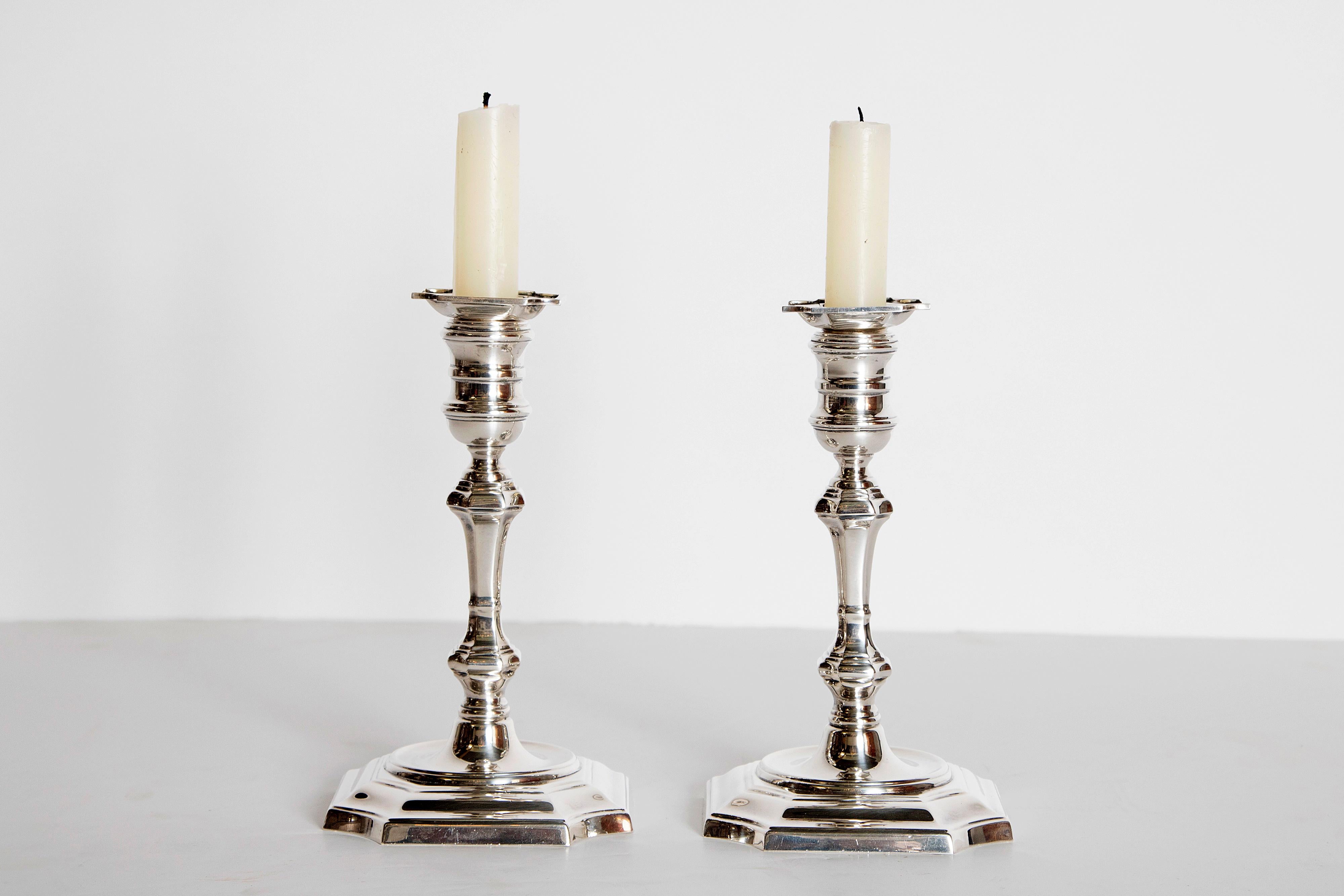 A beautiful pair of George II style candlesticks with octagonal bases with oval borders. The molded stems are topped with octagonal bobeches. Brand stamp and hallmark on underside. United States, 20th century.