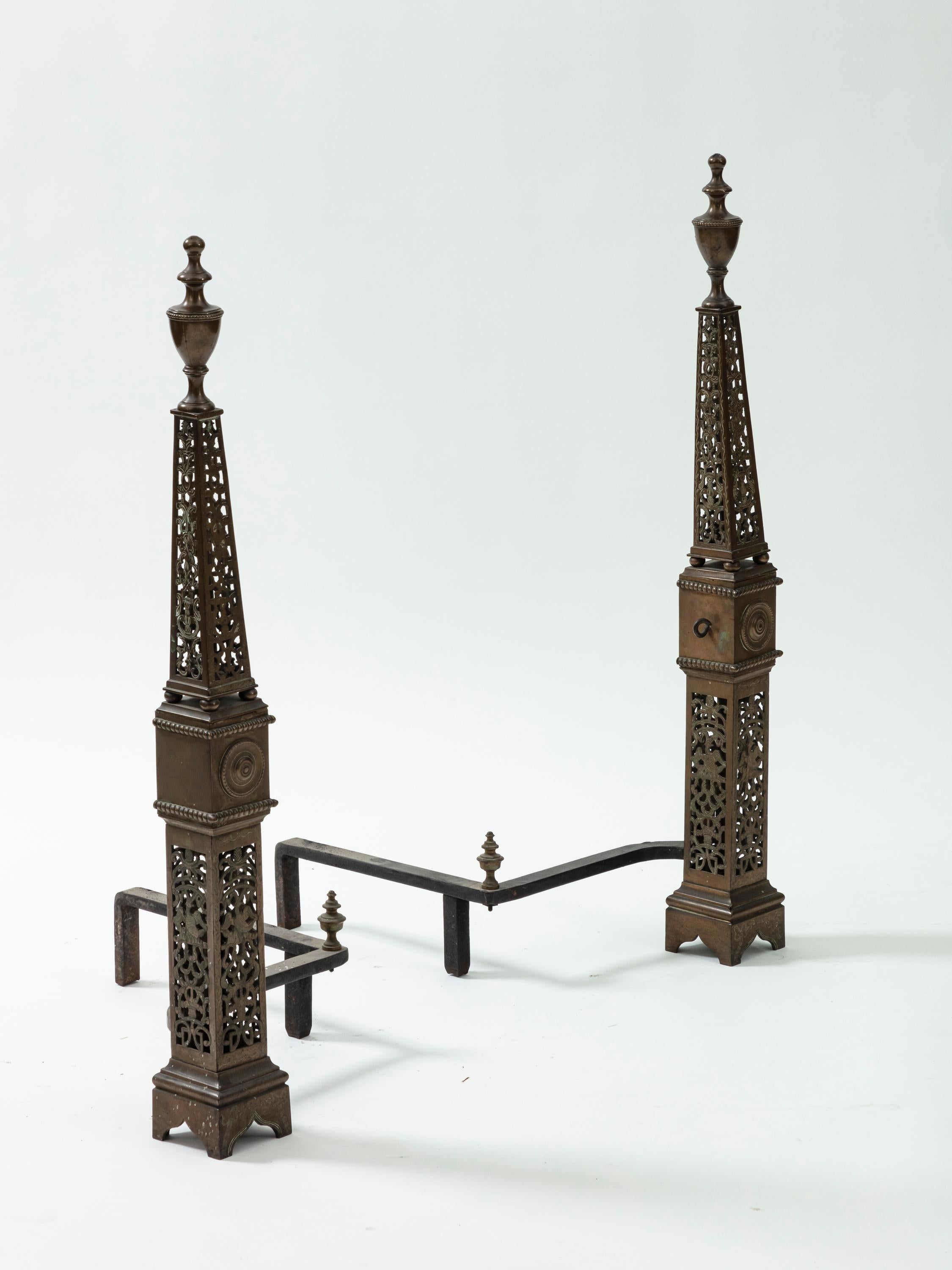 Pair of English George III bronze andirons. Fine openwork in chiseled bronze in the shape of an obelisk. England, circa 1820.