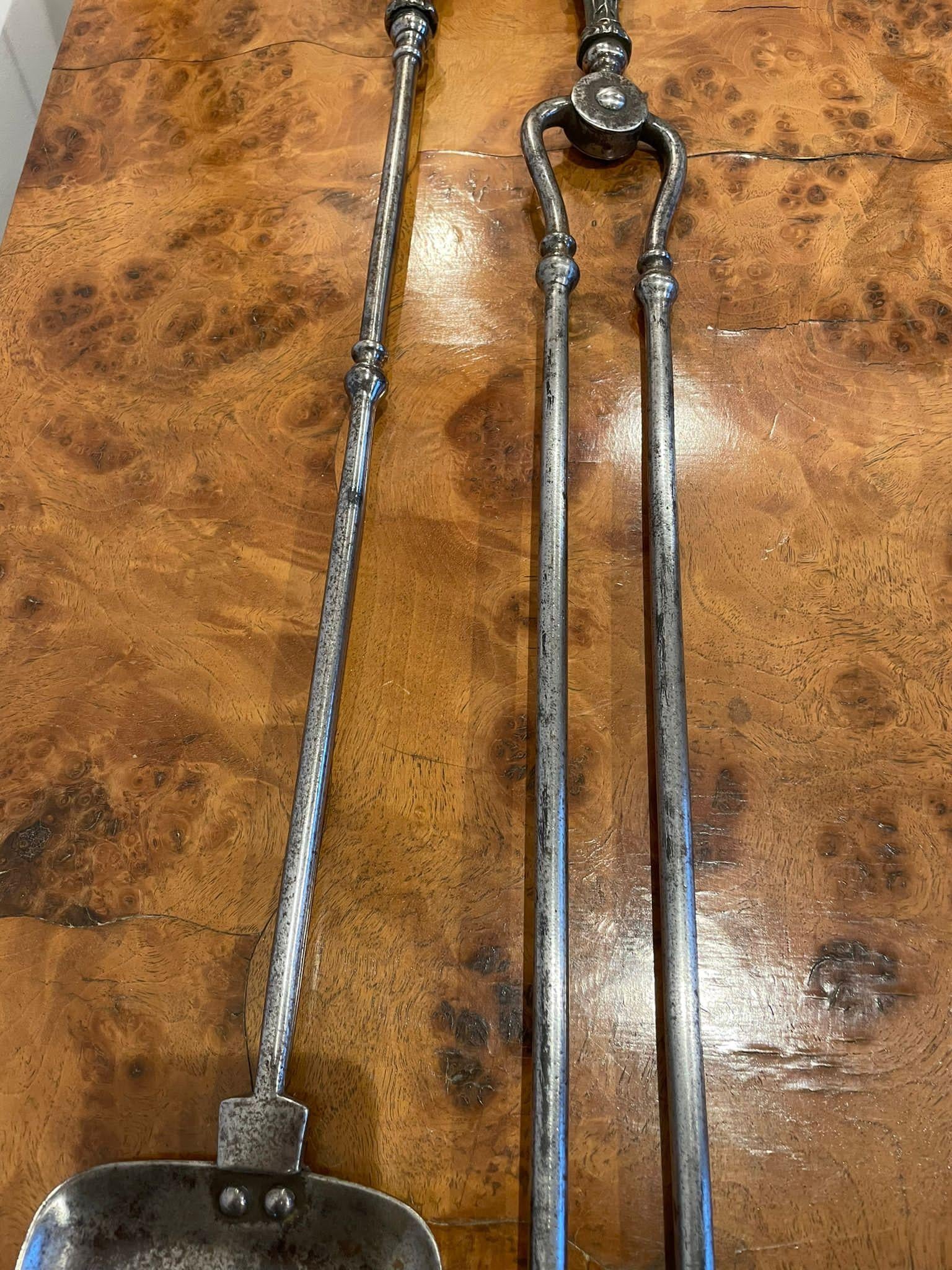 Pair of George III antique steel fire irons consisting of a pair of steel fire tongs and a shovel with a pieced centre.

Measures: 73.5 x 12 x 3cm 

Date 1780.
 