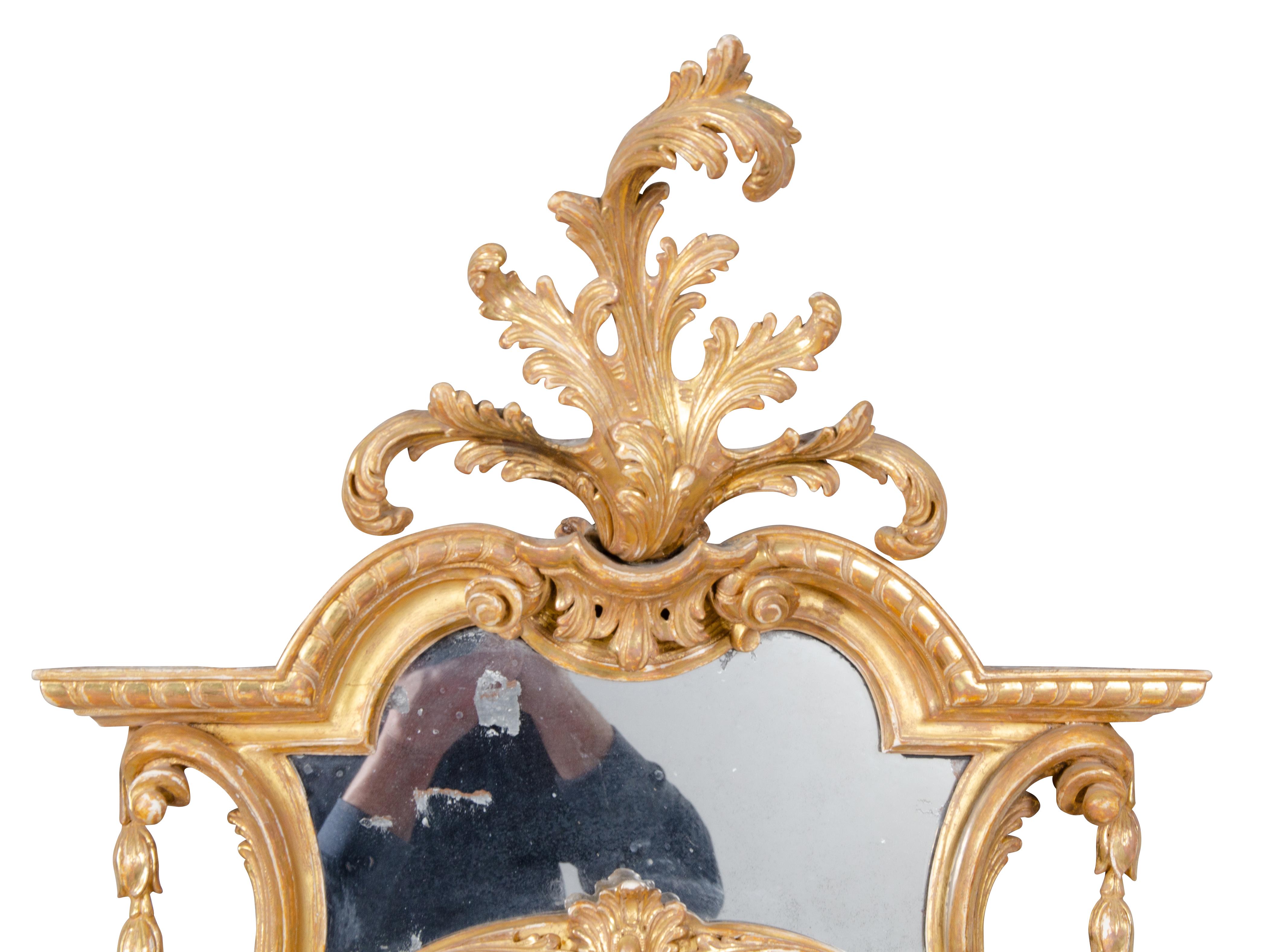 These exquisite mirrors sold at Christie's twenty years ago. With great surface and the best quality gilding. The crest with leaf spray over an arched top and glass panel over an oval plate. Four mounted metal candle arms. The whole within a carved