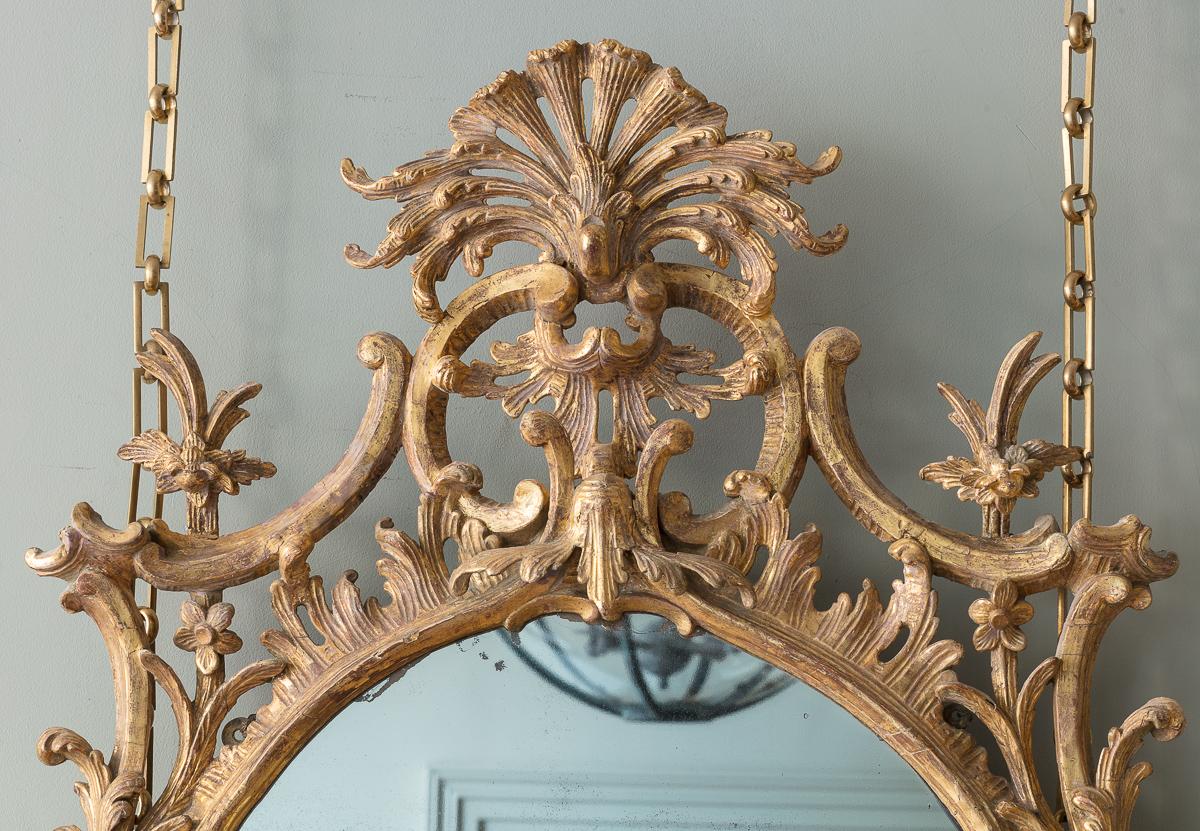 A Pair of George III Giltwood Wall Mirrors, c.1780. With extensive foliate and c scrolling details, with exceptional movement in the carving, carefully stripped back to reveal the original 18th Century gilt surface. With associated 19th century
