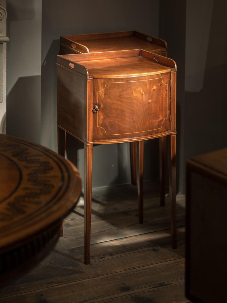 An exceptional pair of George III mahogany and box wood strung bedside cabinets, with bow front outline on square tapering legs, circa 1790.