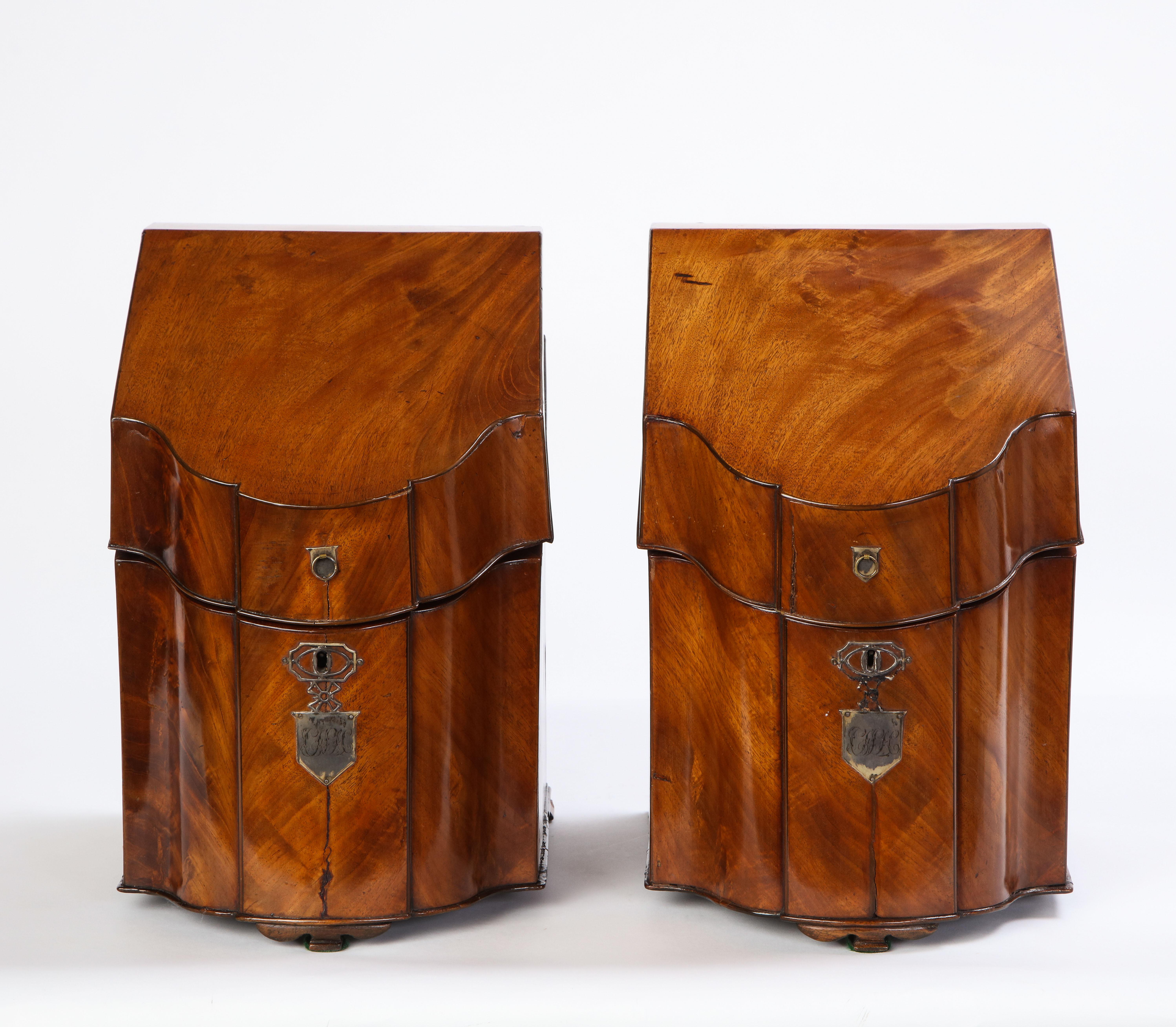 Pair of George III mahogany cutlery boxes, late 18th century. Each with a sloping serpentine-fronted hinged top enclosing a fitted interior, each with plaque engraved with script initials.

With a clean, complete well-maintained appearance,