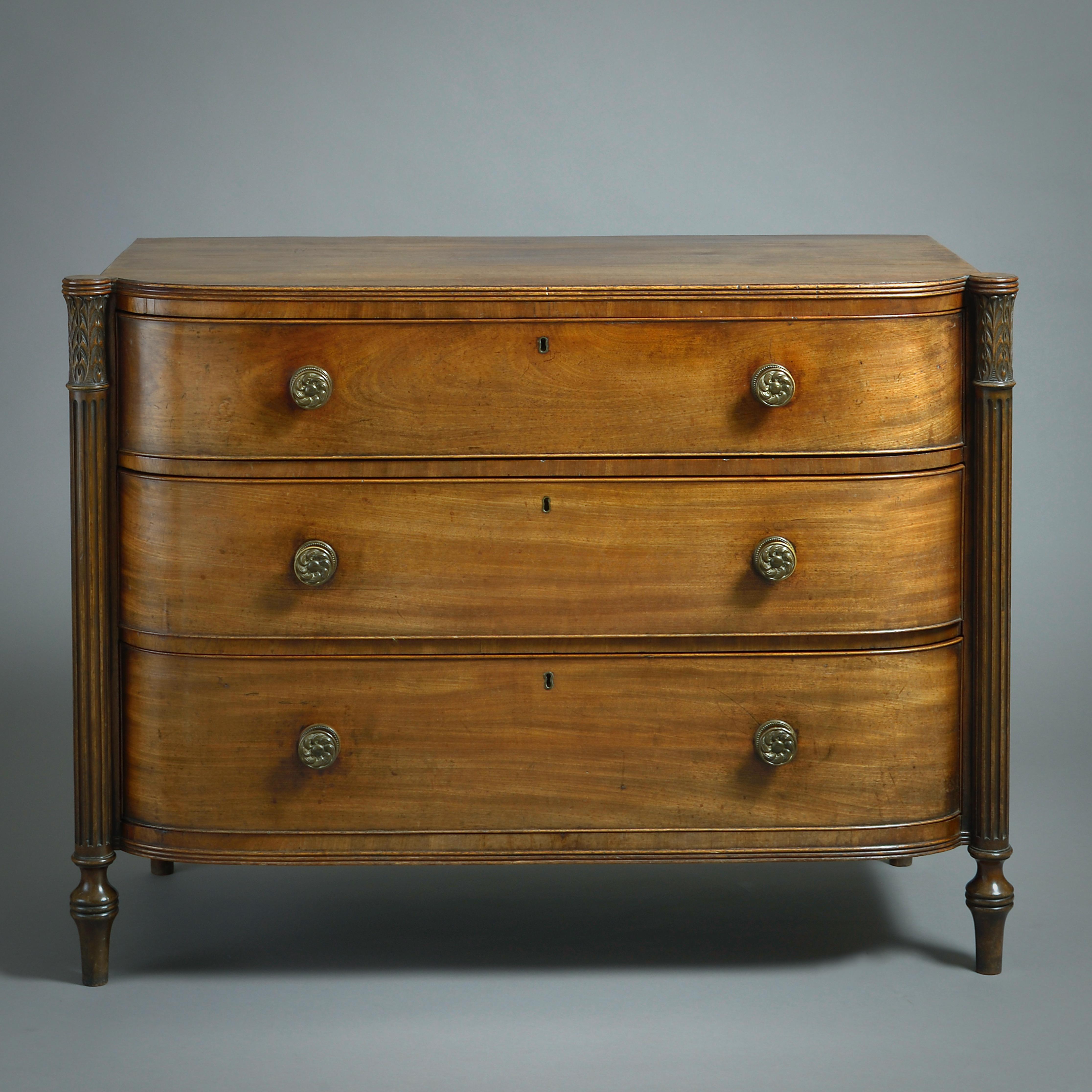 A FINE PAIR OF GEORGE III MAHOGANY D-SHAPED COMMODES, CIRCA 1800.

Each with three drawers fitted with their original brass handles between reeded three-corner columns with stiff-leaf capitals.