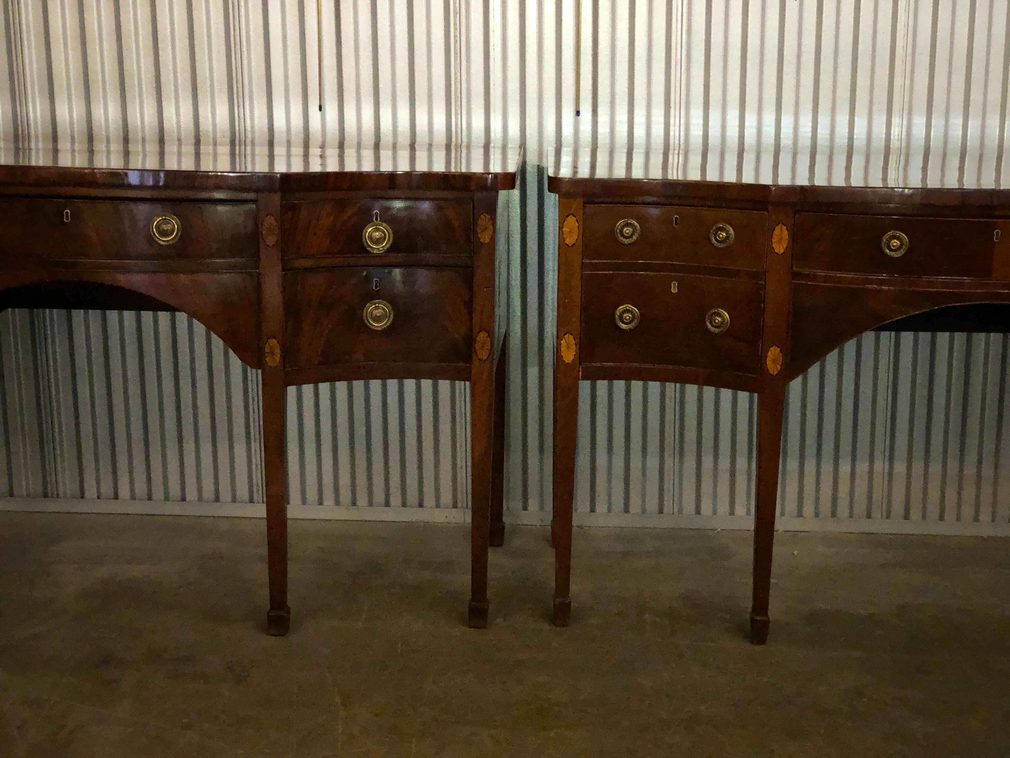 A matched pair of George III mahogany serpentine form sideboards with satinwood oval fan inlays raised on square tapered legs. 

Measures: One: 66