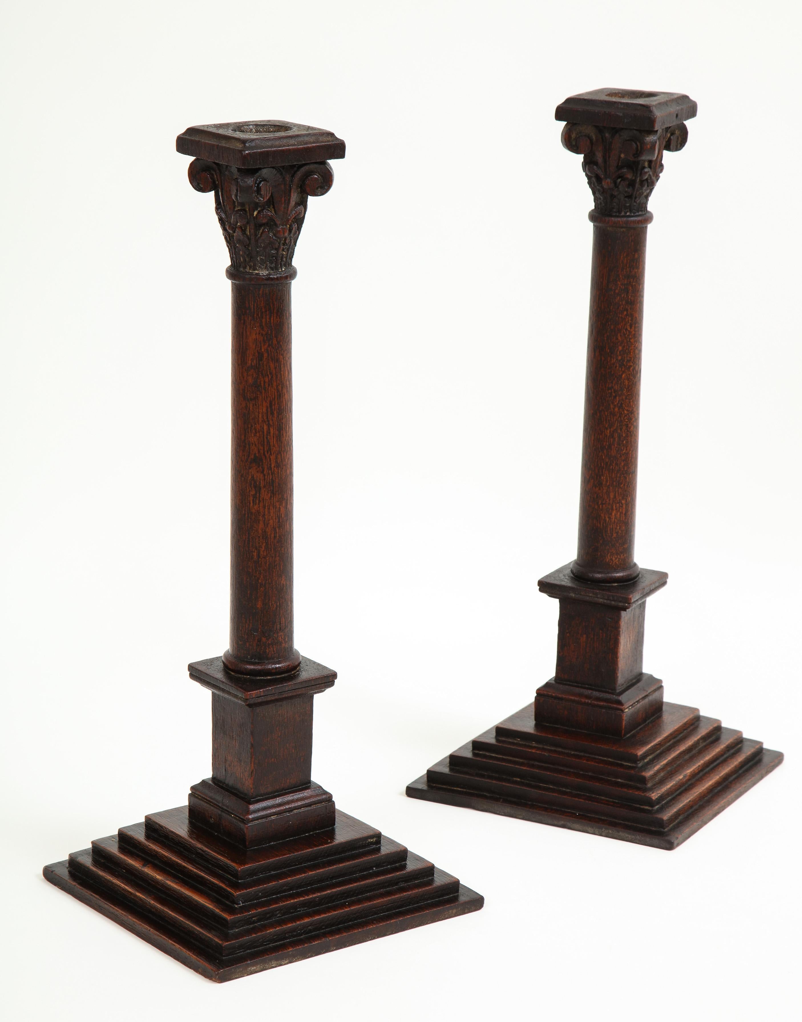 Each with deep brown patinated surface and in the form of a column from the composite order which combines the volutes of the ionic order with the foliate capital of the Corinthian; on a stepped plinth base. Beautifully carved.