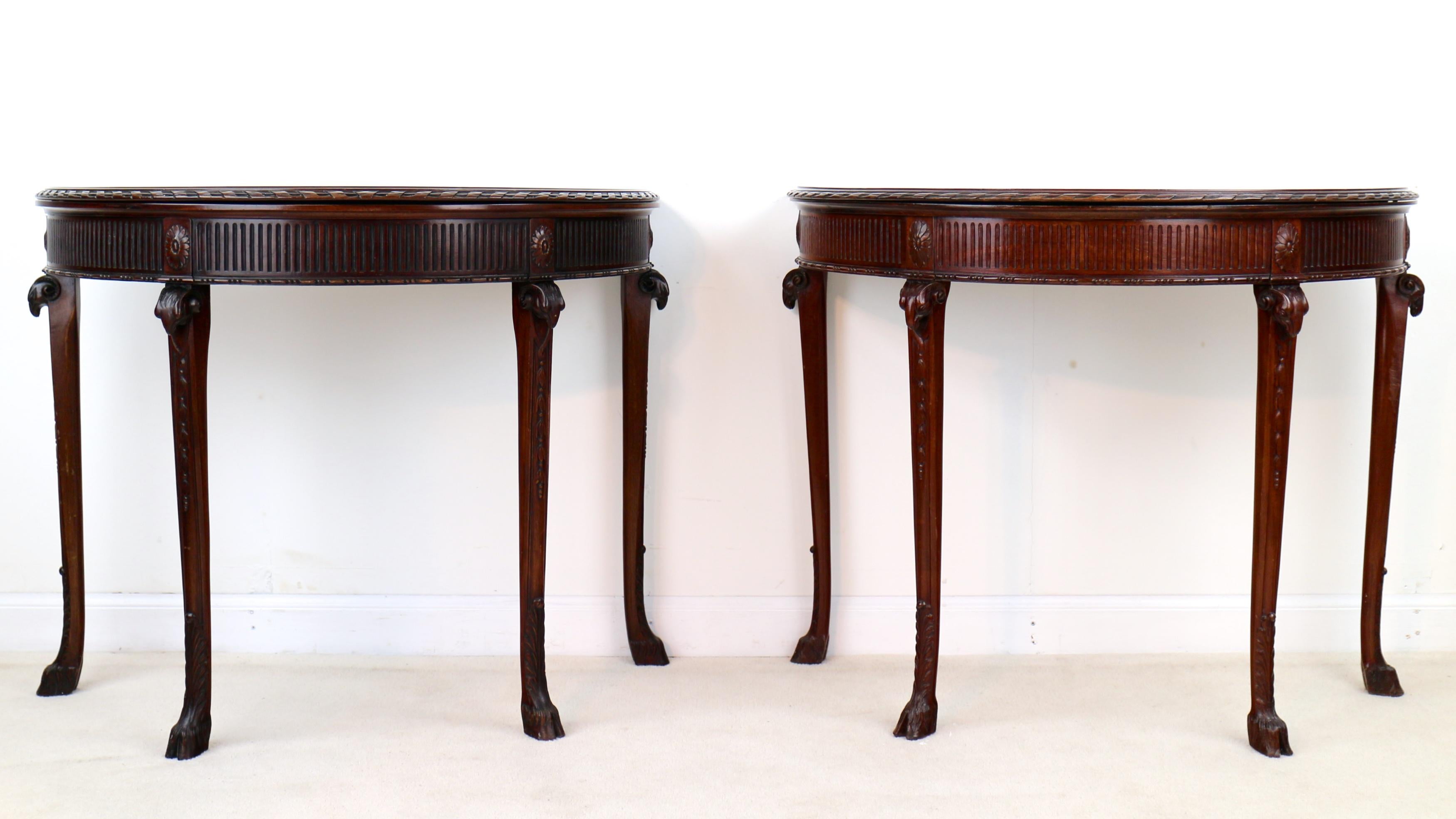An elegant pair of George III style mahogany demo-lune card tables by Maples & Co and dating to circa 1900. These unusual tables are designed after the Neoclassical style of Robert Adam and Thomas Chippendale as found in Paxton House in Scotland.