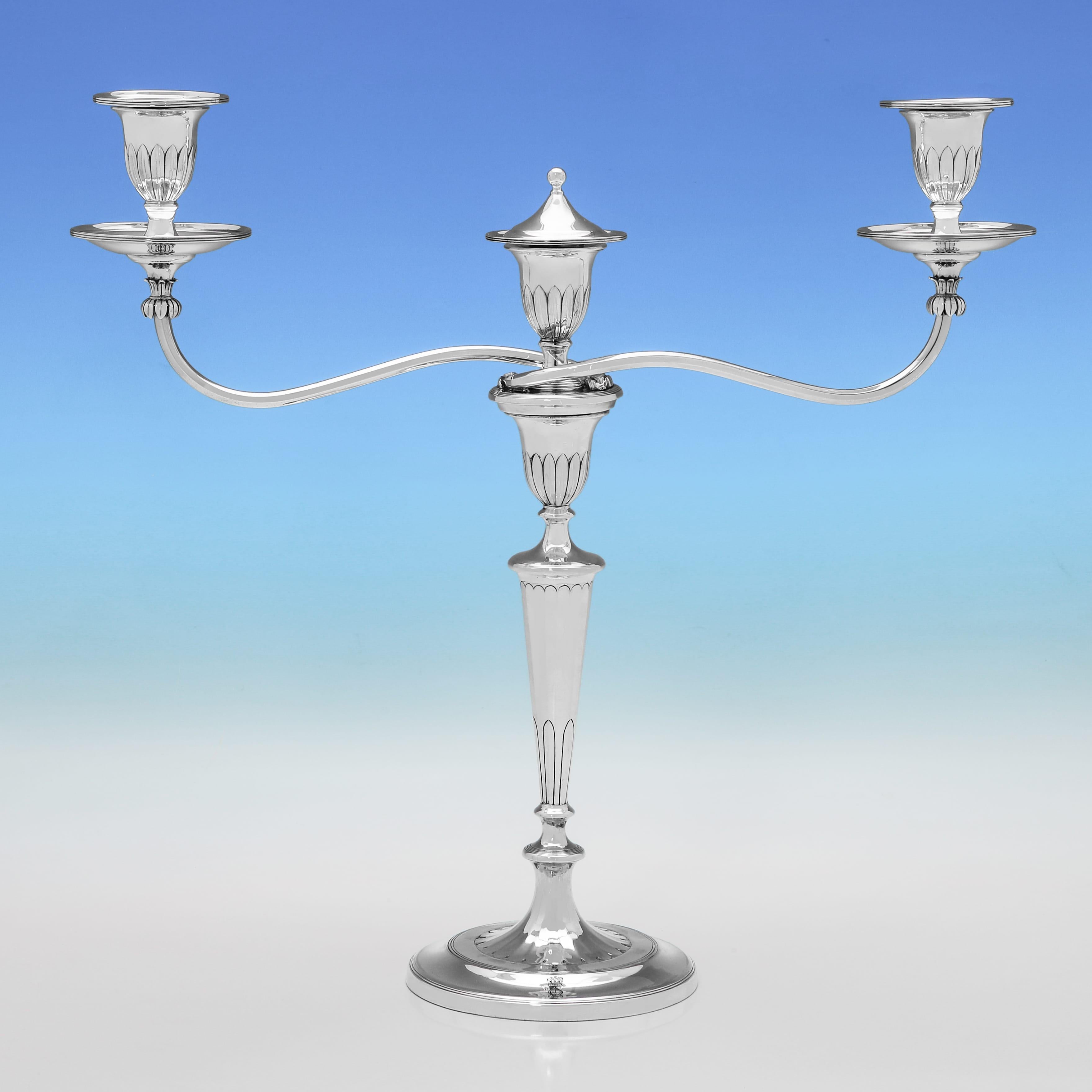 Hallmarked in Sheffield in 1799 by John Green & Co., this elegant pair of George III period, Sterling Silver three-light candelabra exhibit refined neoclassical design, with tapering columns, reeded detailing, and detachable arms and nozzles for