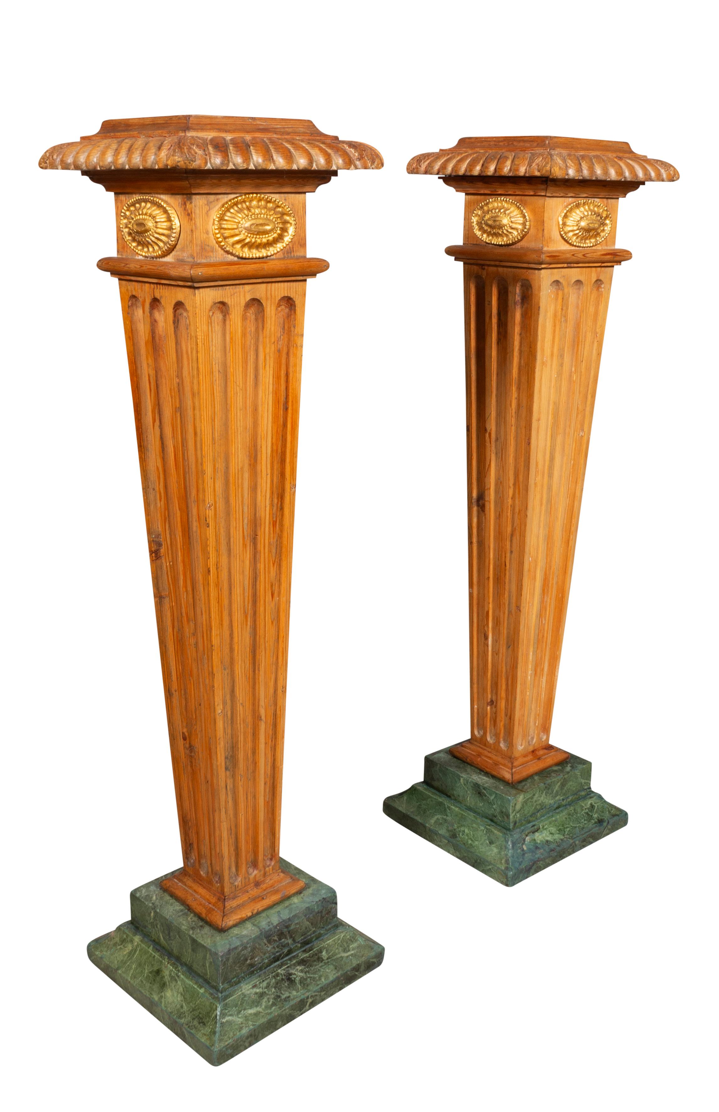 Chacune présente un plateau carré à bord godronné sur des paterae en bois doré et une colonne cannelée effilée reposant sur un socle en faux marbre vert. 