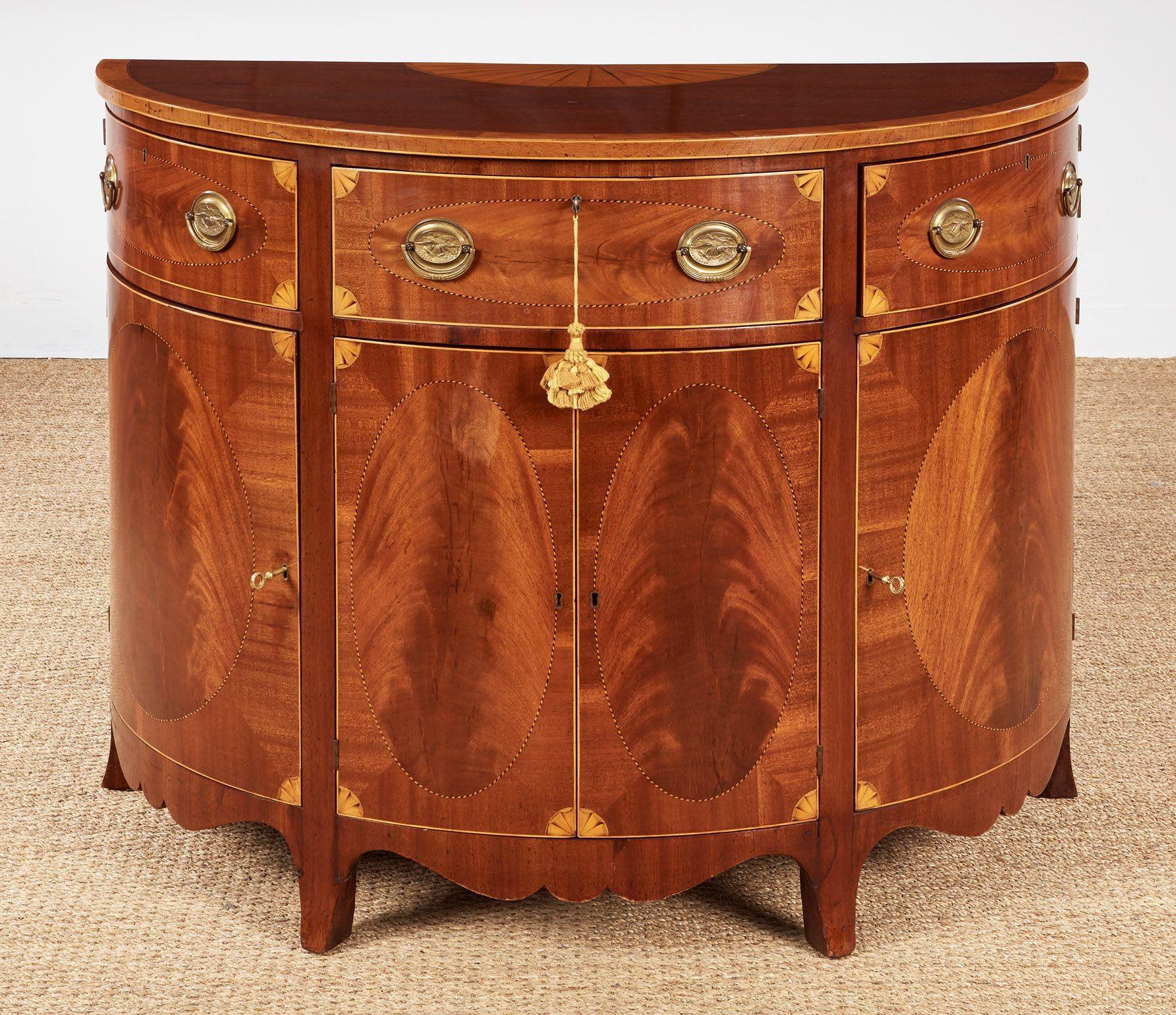 Fine pair of George III mahogany demilune commodes with satinwood banded and fan inlaid tops over half round case having three drawers and four doors, each with quarter fan inlaid corners and standing on splayed French feet, the whole in good rich