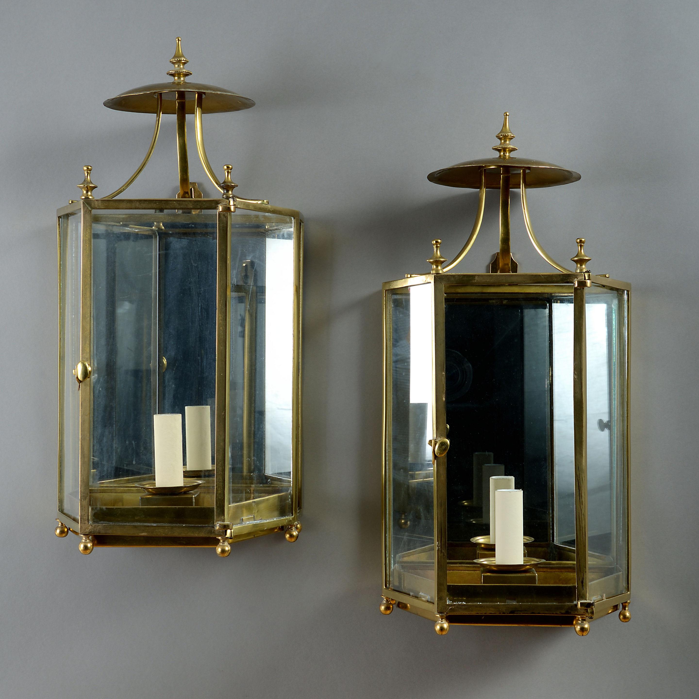 A pair of mid-20th century brass hall lanterns in the Georgian taste, of faceted form, having smoke cowls set with finials. 

Wired for electric lighting.
   