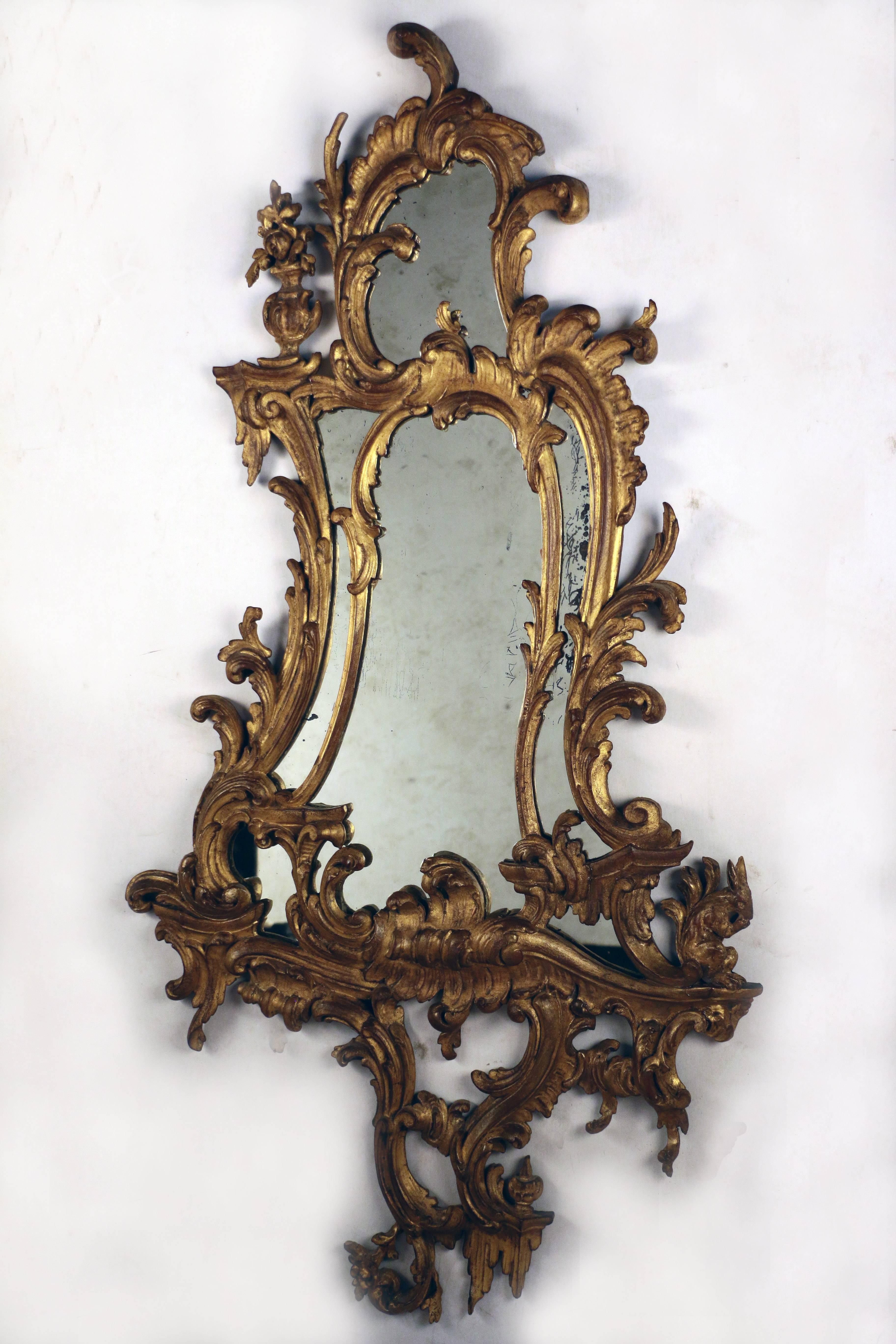 À la manière de Thomas Chippendale (1718-1779)

Une paire exceptionnelle de miroirs en bois doré de style George III, la plaque de miroir dans un cadre cartouche asymétrique sculpté et moulé à la manière rococo de Thomas Chippendale avec une