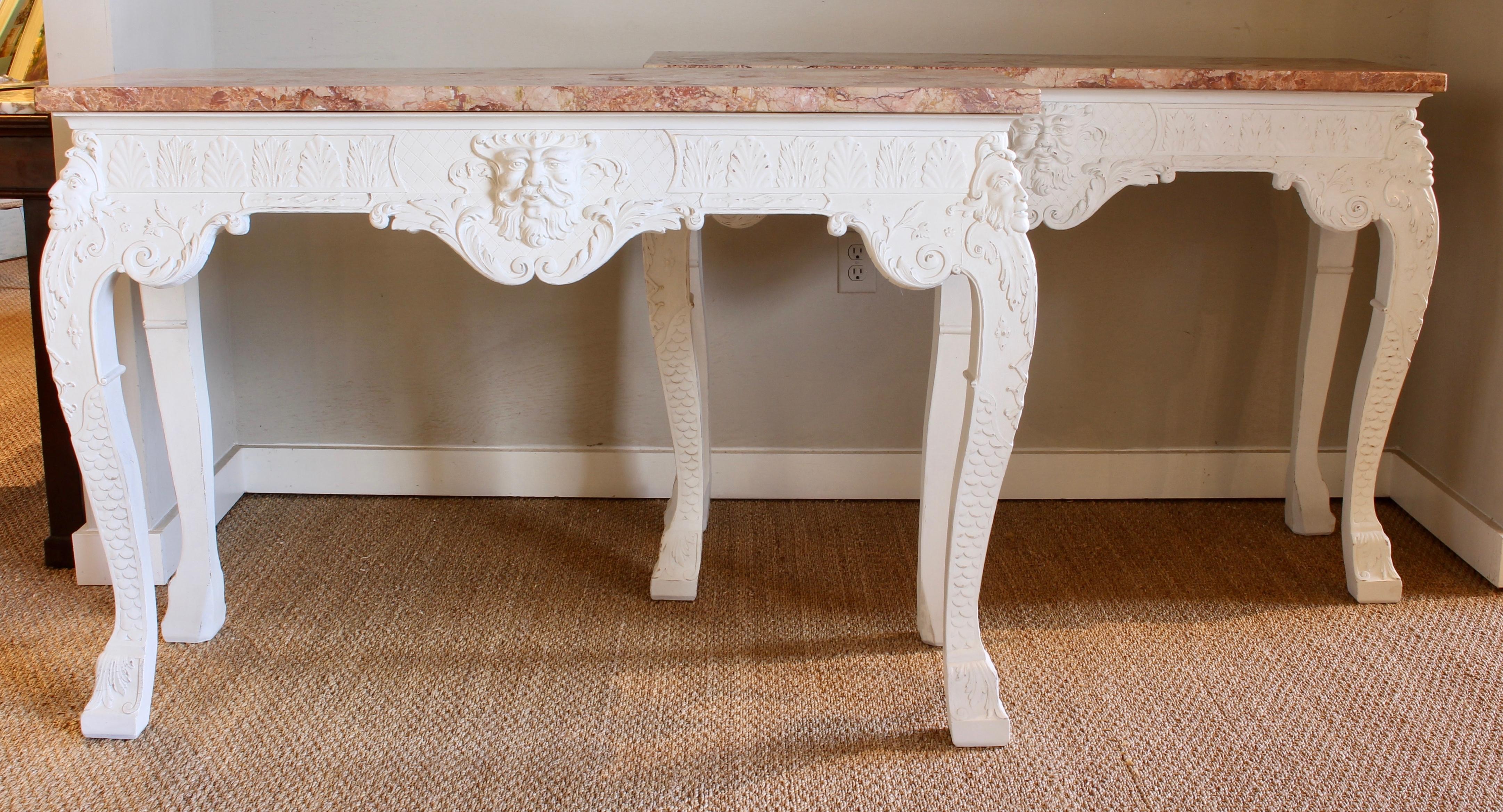 A pair of George III style elaborately carved and gessoed console tables with rouge marble tops.