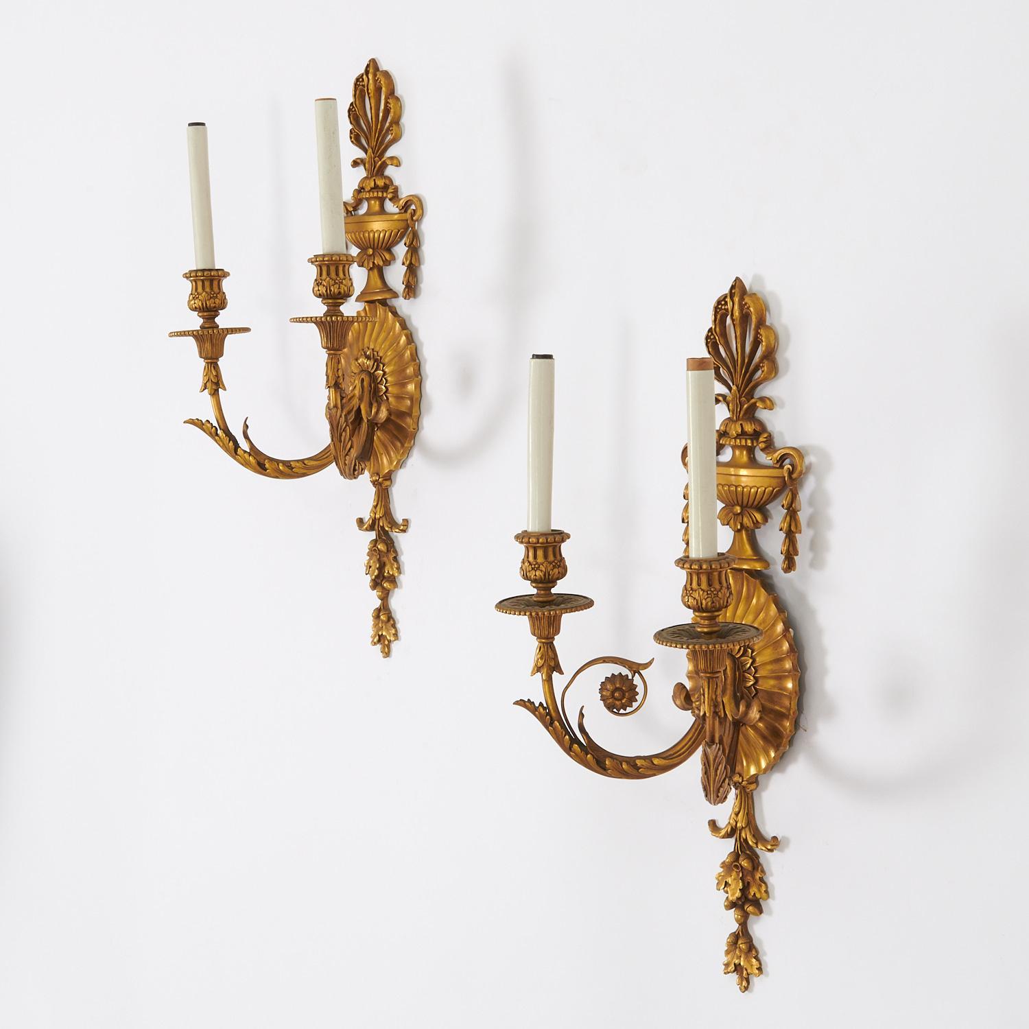 An elegant pair of George III style gilt bronze wall light sconces
Each sconce with two arms issuing from a channeled oval backplate topped with an urn and plume finial, impressed manufacturer mark on reverse,

Maker: Edward F. Caldwell Co.