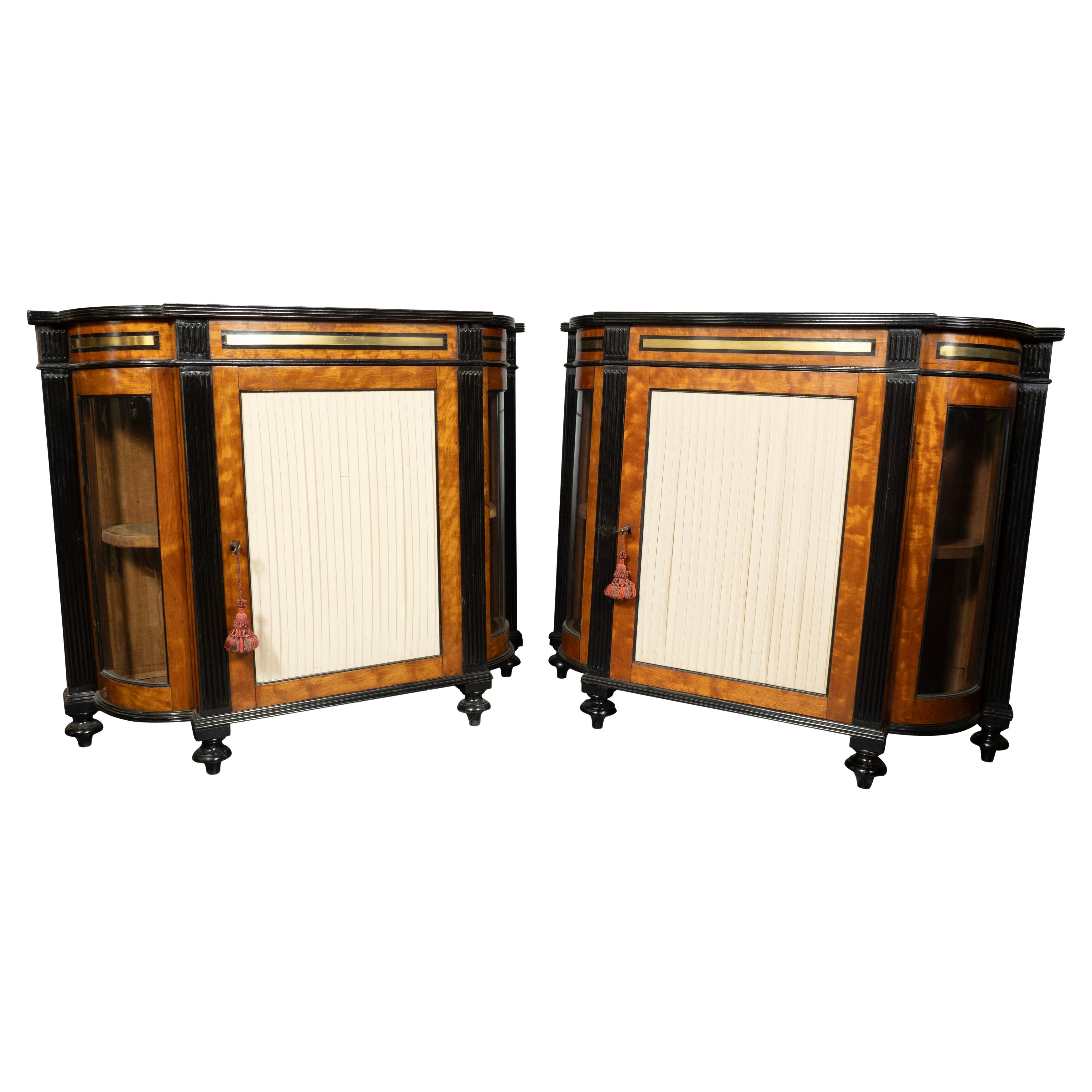 Each with a bowed top with brass and ebony inlay. Conforming case with a frieze with brass mount over a central door flanked by reeded ebonized pilasters and bowed glass panels. Toupie feet. Door panel now pleated silk can be replaced with glass.