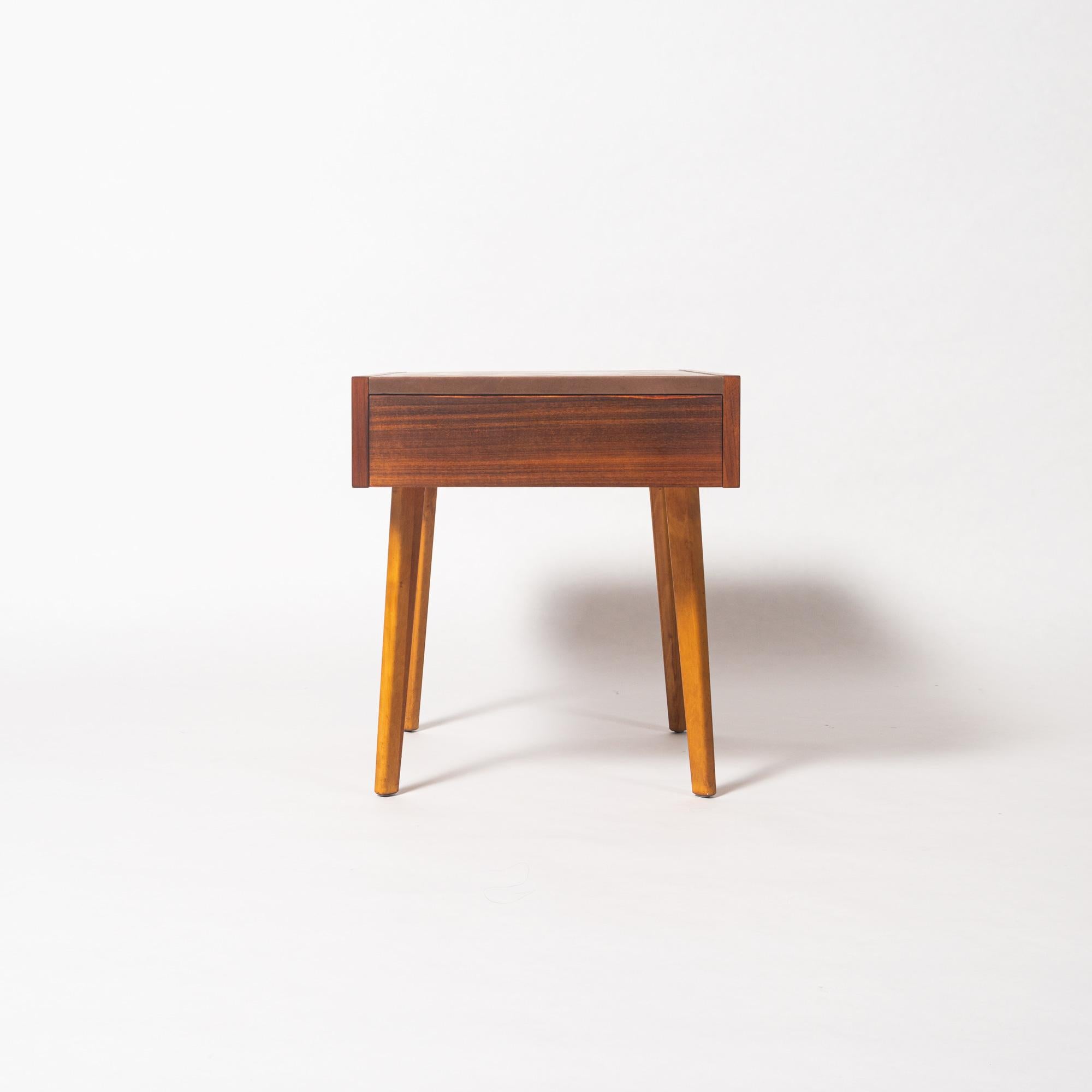 A pair of small end tables with drawer by George Nelson for Herman Miller. The table is made of a teak frame with tapered legs and a brown leather top. circa 1950s. This item will be delivered by one of our trusted furniture delivery company, and