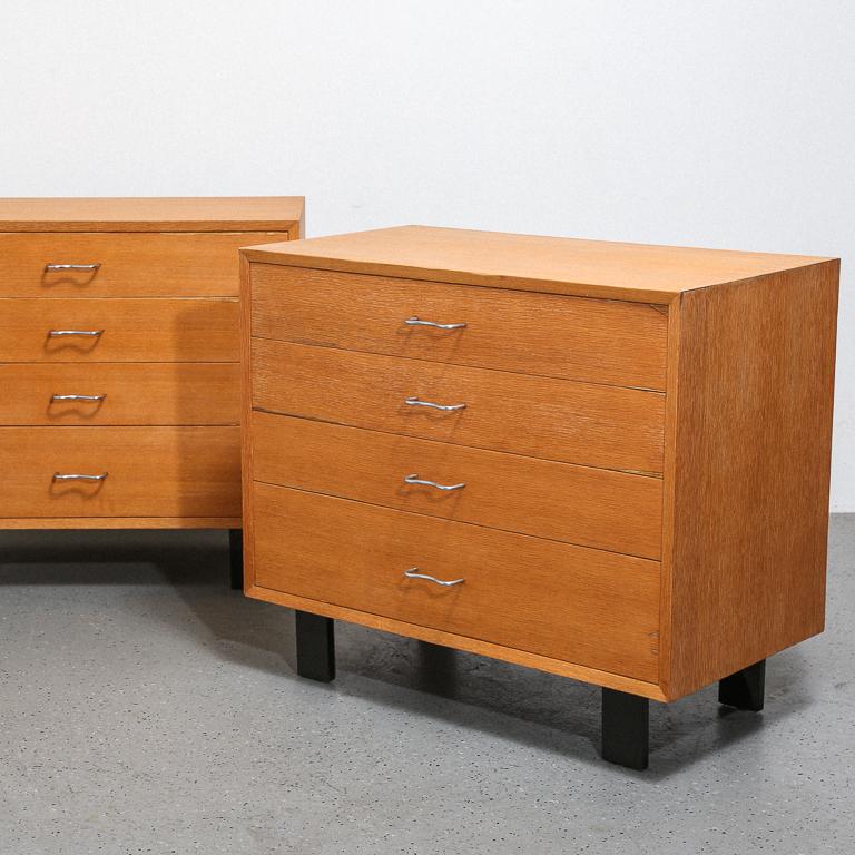 Original pair of George Nelson 'Basic Cabinet Series' dressers for Herman Miller. Primavera veneer with black painted legs and stainless M-pulls. Both retain their foil Herman Miller decals.