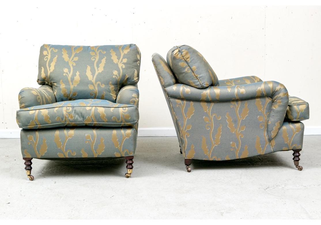 Pair of George Smith custom upholstered signature lounge chairs with rolled English arm and feather filled cushions. The chairs with loose pillow back and seat, turned front legs and tapering back legs all with brass casters.

Dimensions: 32