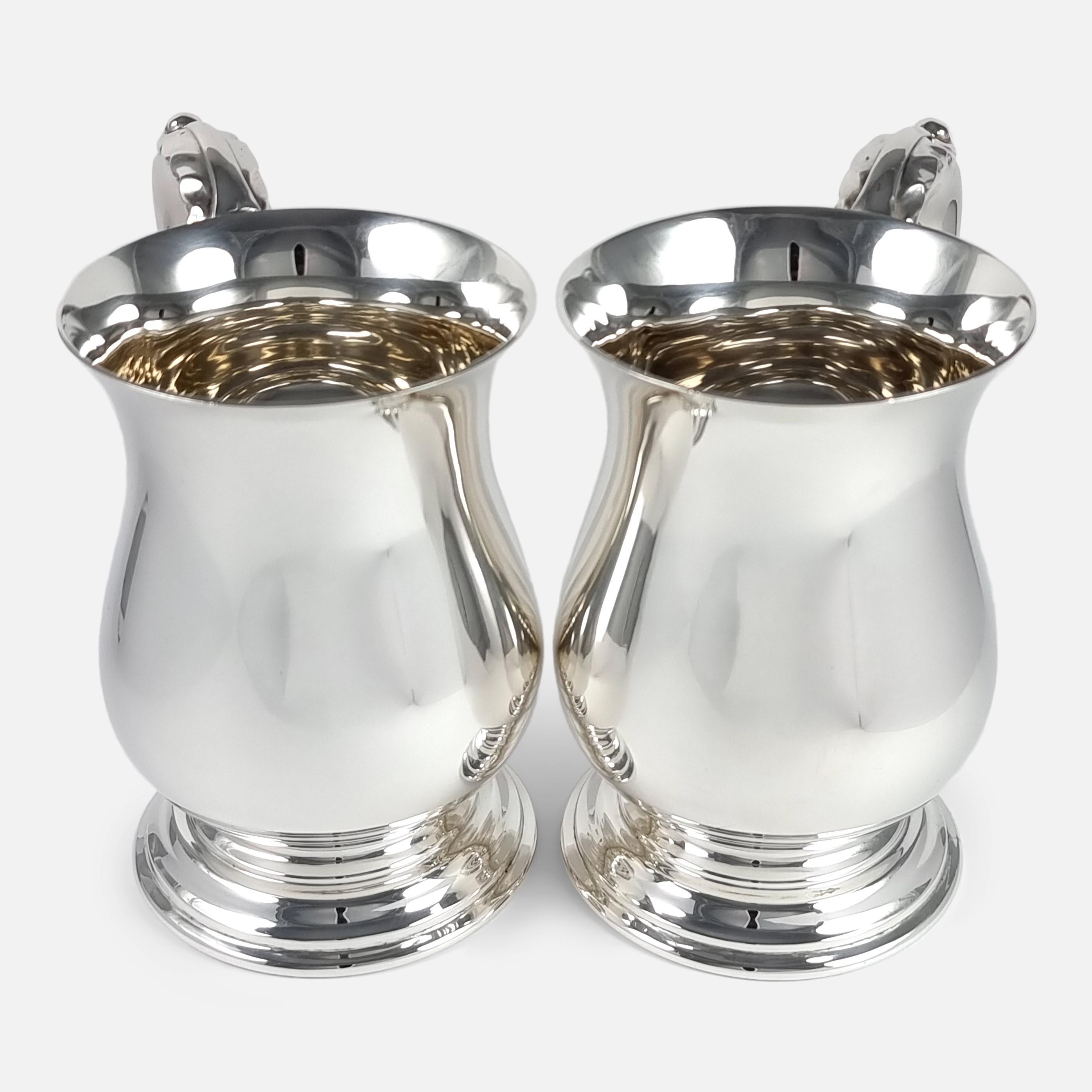 A pair of George VI sterling silver mugs. The mugs (or tankards) are crafted in the George III style, of baluster form upon a spreading circular foot, with acanthus capped double C scroll handles.

The pair of mugs are made by Stower & Wragg Ltd,